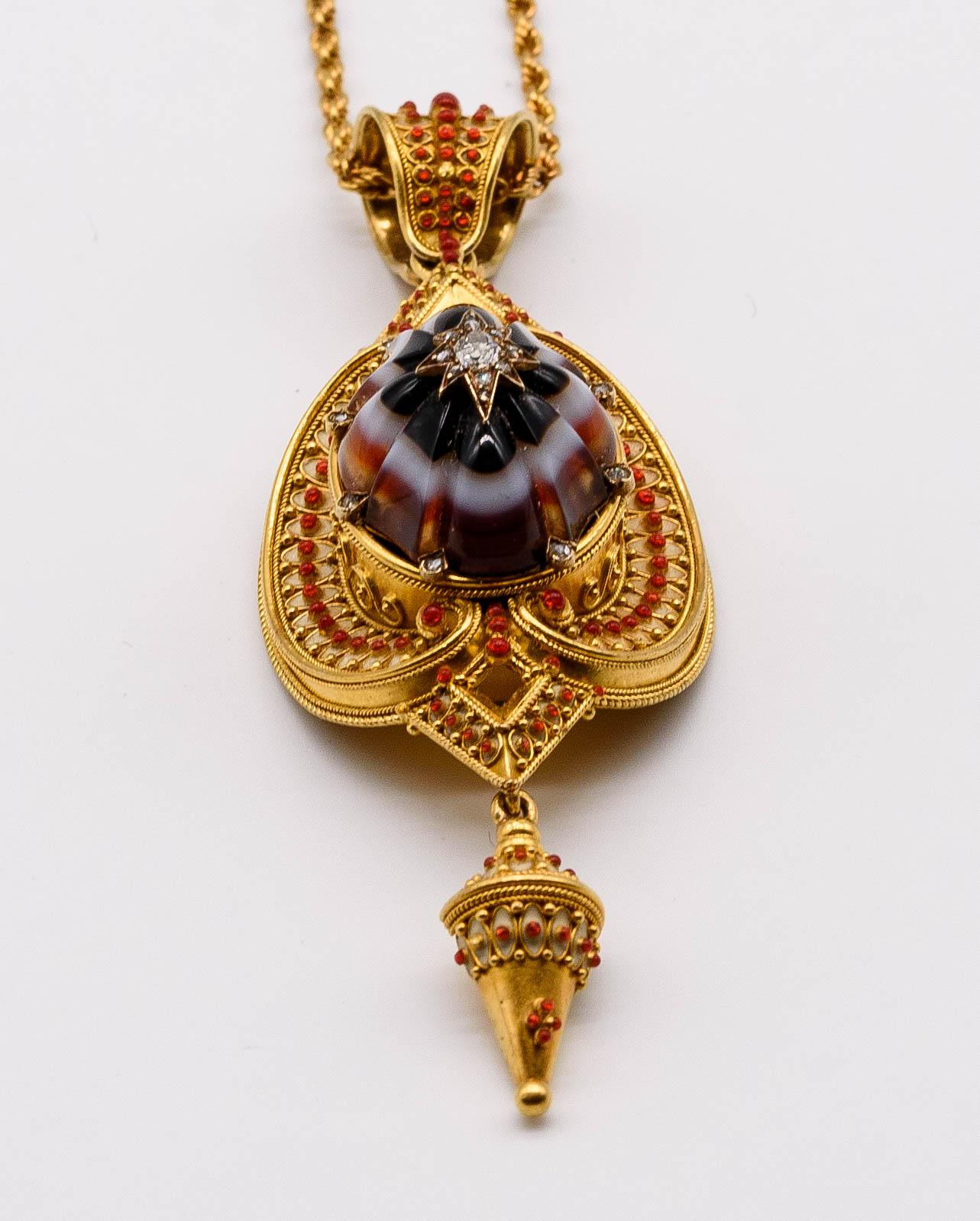 This delightfully complex pendant holds a plethora of noteworthy details.  Crafted in 18 karat yellow gold, it boasts a melon cut banded agate center with sharply polished edges, the dome leading up to a discreet diamond set star.   The motif is