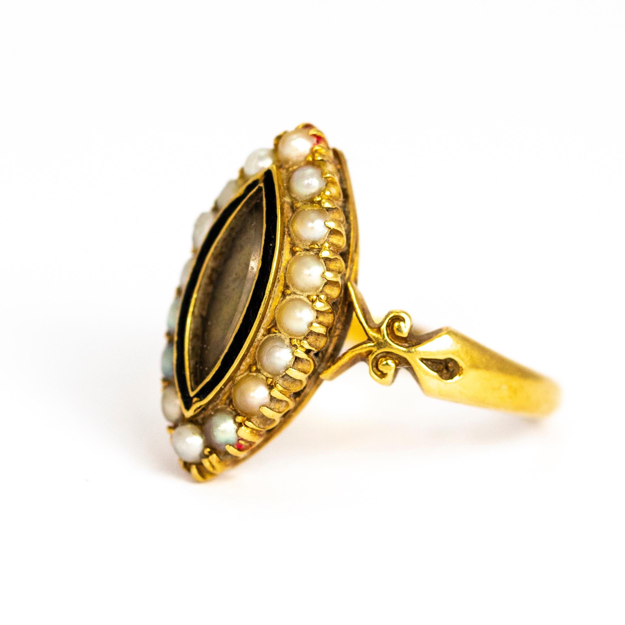This spectacular antique mourning ring dates back to the late Victorian era. The centre of it's navette front is set with a glazed locket, bordered with black enamel and gold. The perimeter is lined with stunning white seed pearls. The shoulders
