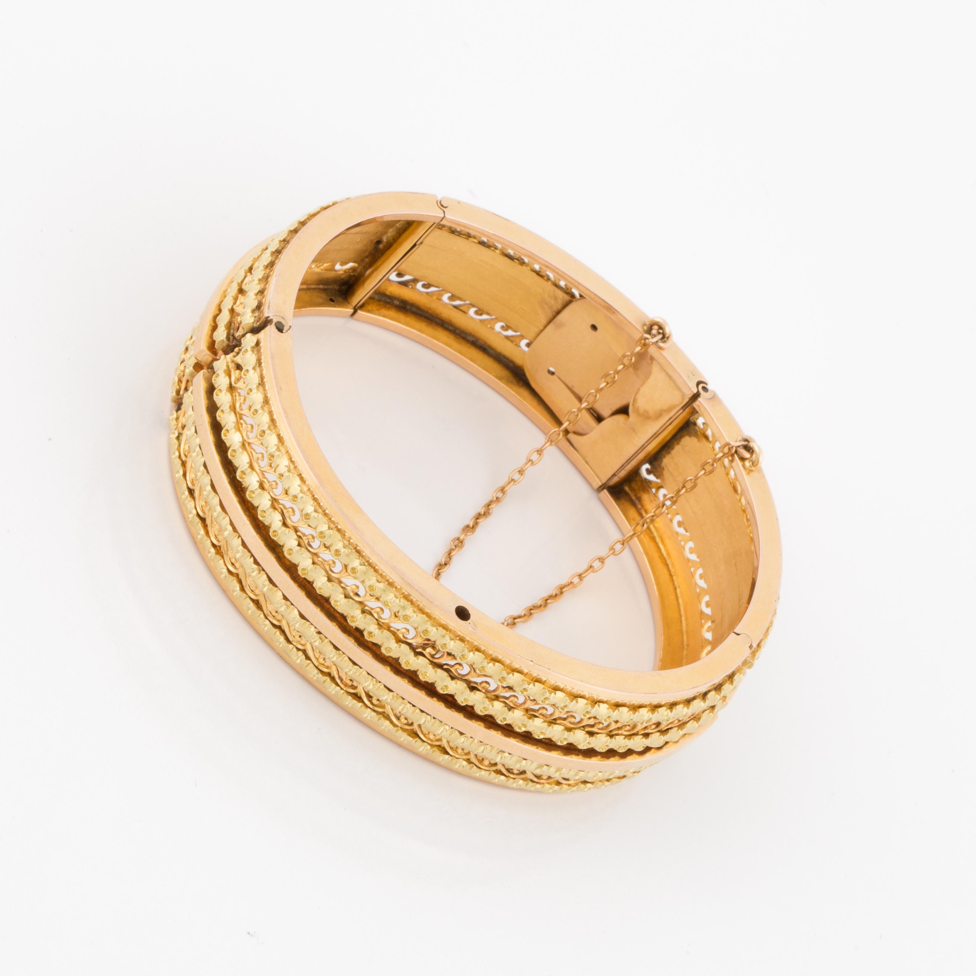 Mid-Victorian bangle in 18K yellow and rose gold featuring 5 panels hinged together making the bracelet more flexible.   Measures 3/4 inches wide and measures 2 1/4 inches at the inside opening.  Tongue closure with safety chain.  Eastern European,