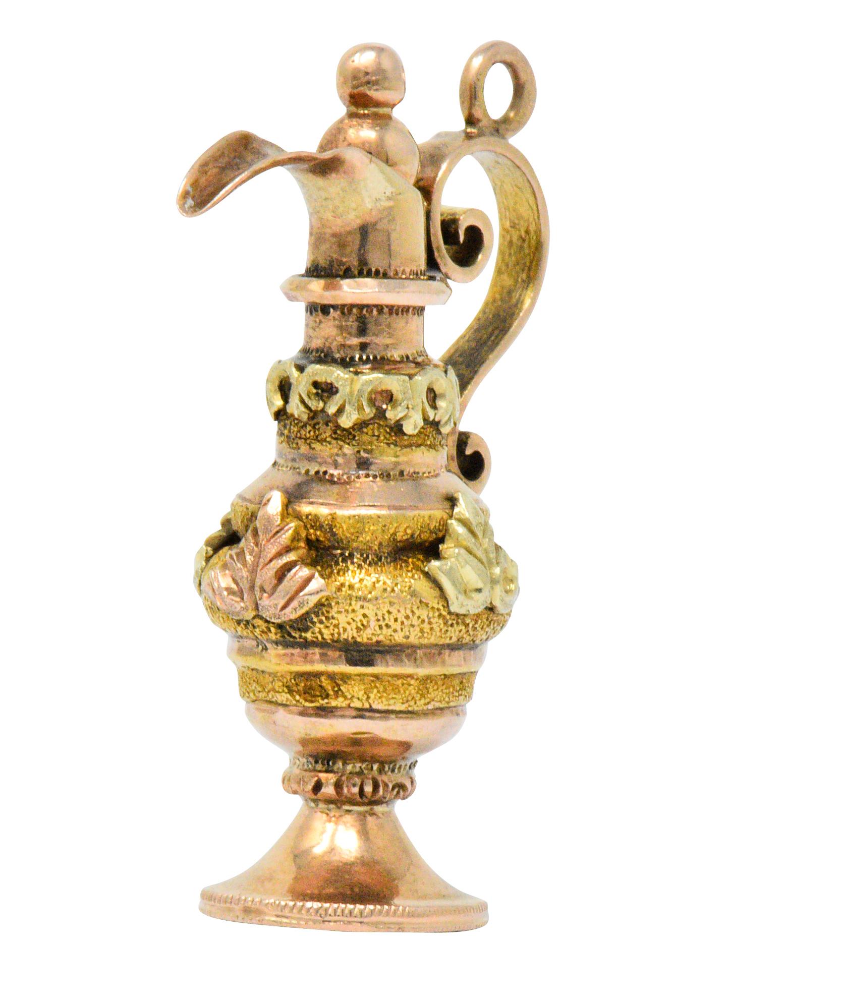 Designed as a highly decorative ewer

With scrolling handle, spout, lid and base

Applied rose and green gold leaves and textured yellow gold on a base of rose gold

Partial maker's mark

Measuring: Approx. 1 1/4 x 3/4 (widest)

Total Weight: 4.4