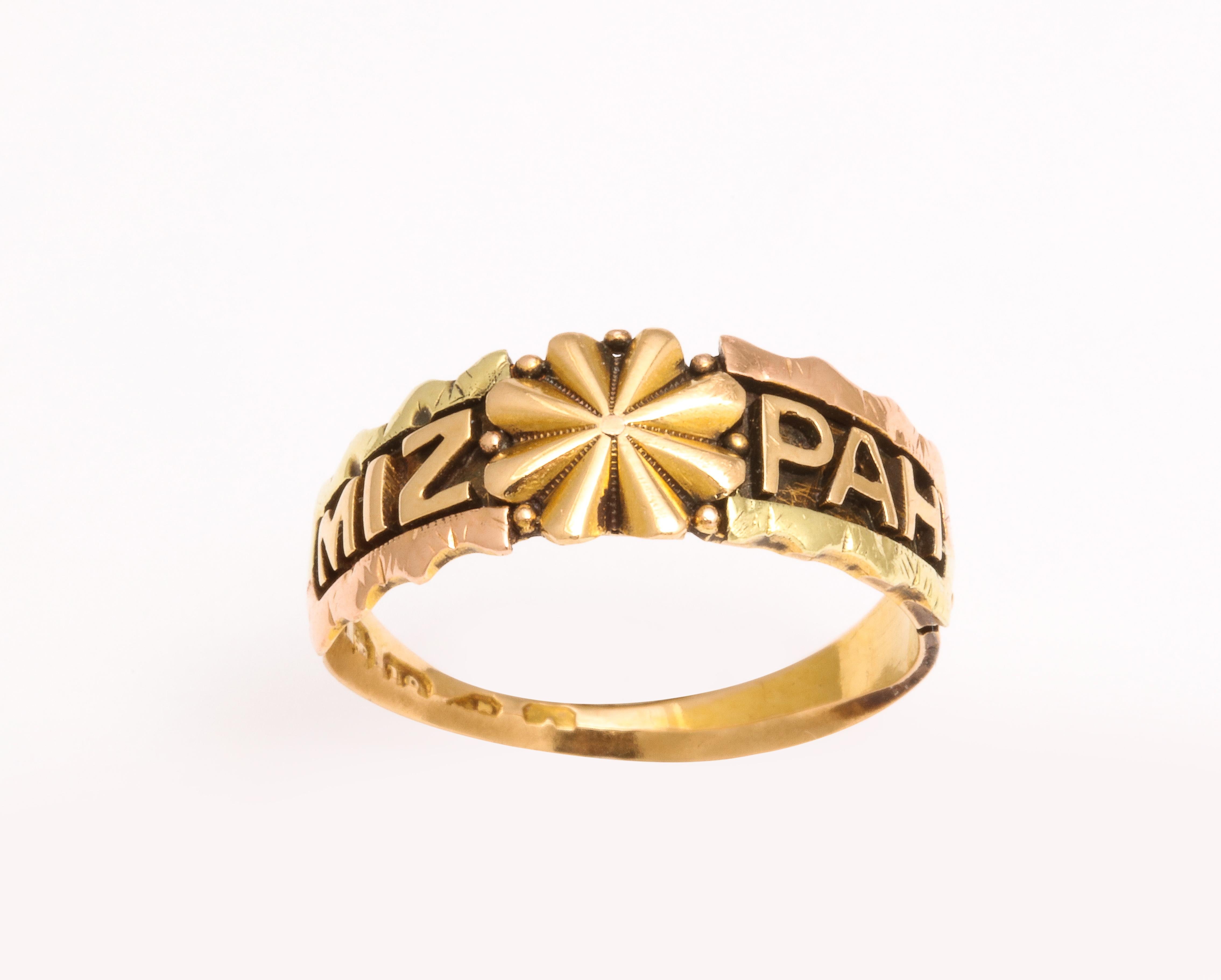 En contraste frappant, cette bague Mizpah a été créée vers 1870 en or 18 carats. En contraste frappant avec l'absence d'usure, le mot Mispah est inscrit en lettres d'or sur un fond d'or plus foncé.  l'arrière-plan. Les bordures sont festonnées. Une