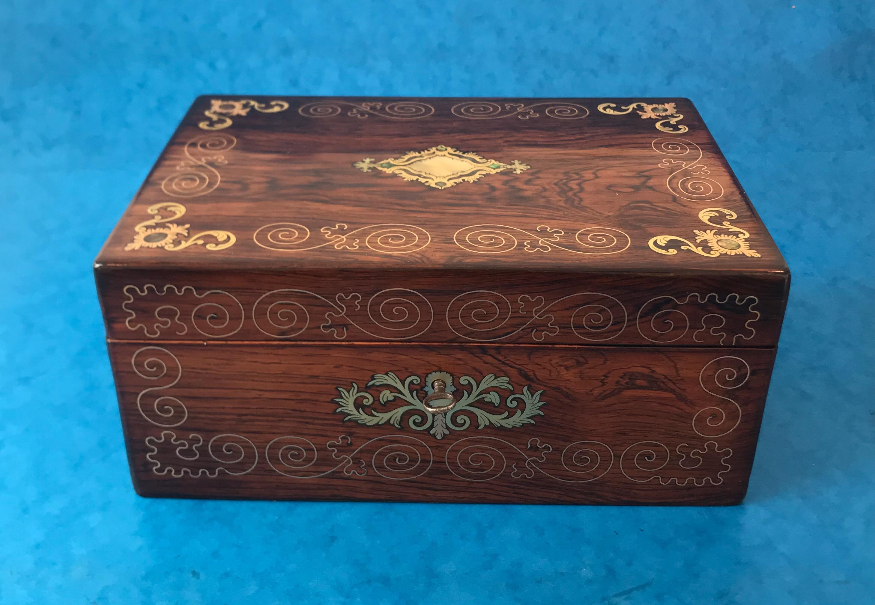 An exquisite Victorian rosewood jewelry box, the jewelry box dates back to 1850. It’s inlaid with brass patterned swirls and swags with inlaid mother of pearl to each centre. The jewelry box houses its original elaborate red interior to the back of