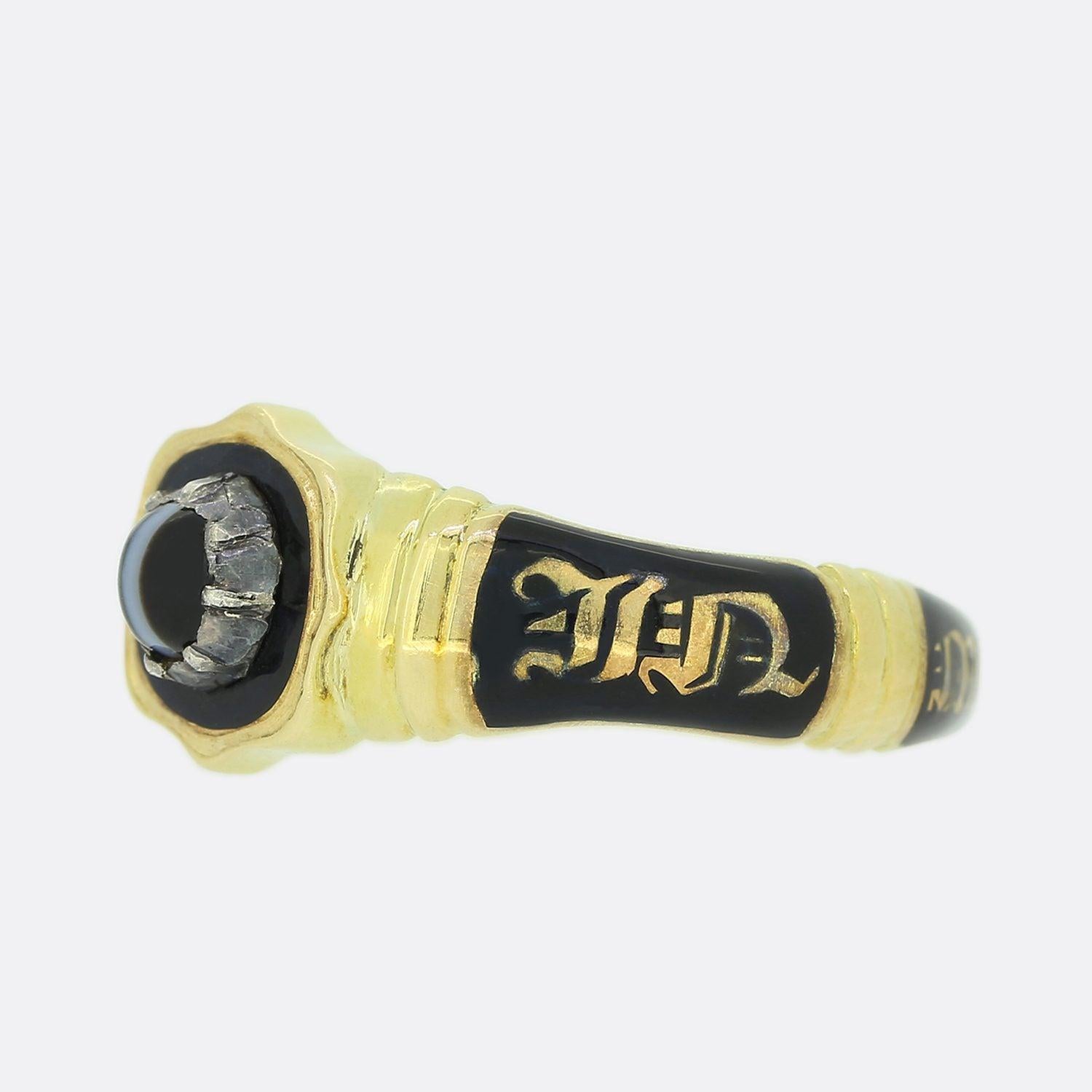 This is a wonderful 18ct yellow gold mourning ring from the early Victorian era. The ring has been set with a central cabochon black cats eye tourmaline and the band of the ring features black enamel with the words 'In Memory Of'. The inside of the