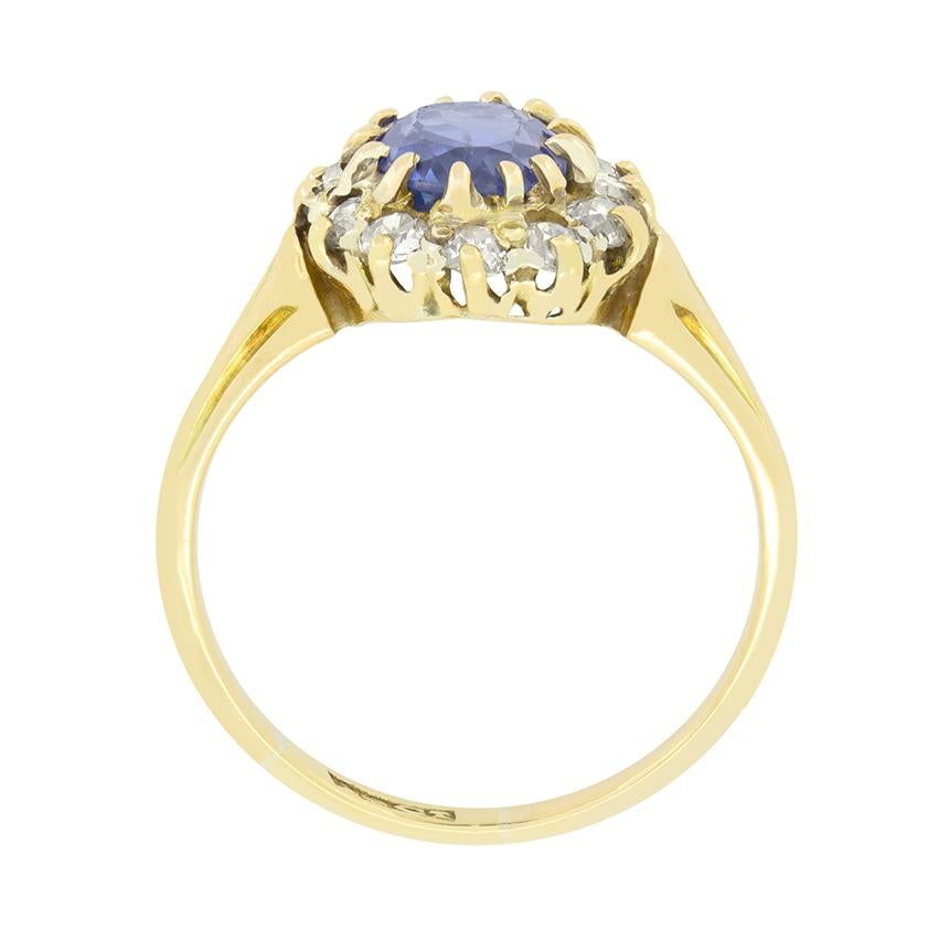 Questo splendido anello vittoriano a grappolo è incentrato su un affascinante zaffiro naturale di 1,85 carati con taglio ovale, sapientemente incastonato. Intorno allo zaffiro blu medio ci sono 0,48 carati di diamanti taglio vecchio, di colore H e