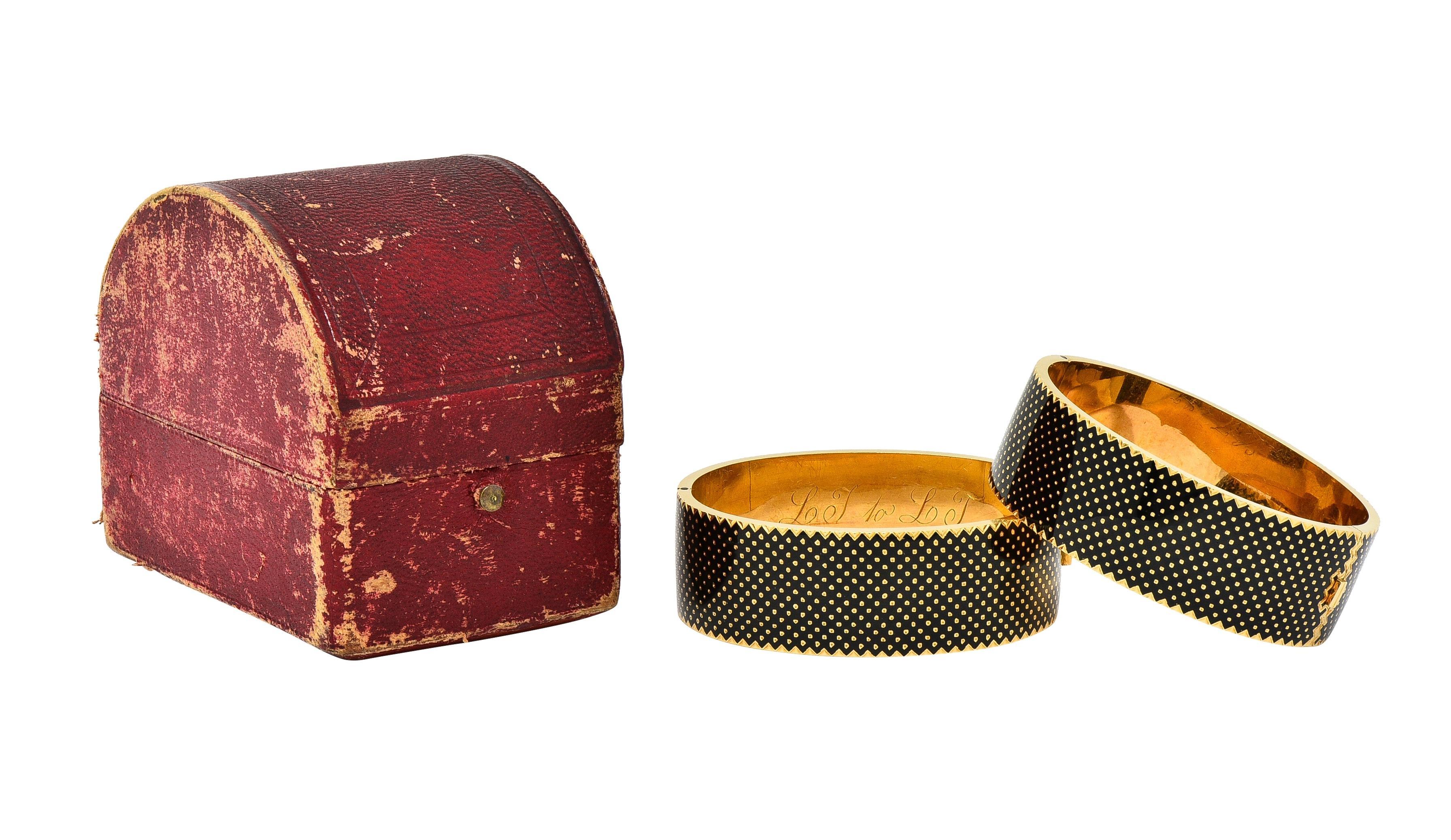 Designed as matching wide gold bangles featuring glossy black enamel panels 
Opaque with chevron motif edges and gold polka dot pattern throughout
Exhibiting minimal loss - each inscribed 'L.J. to L.T.'
Both open on a hinge via press release