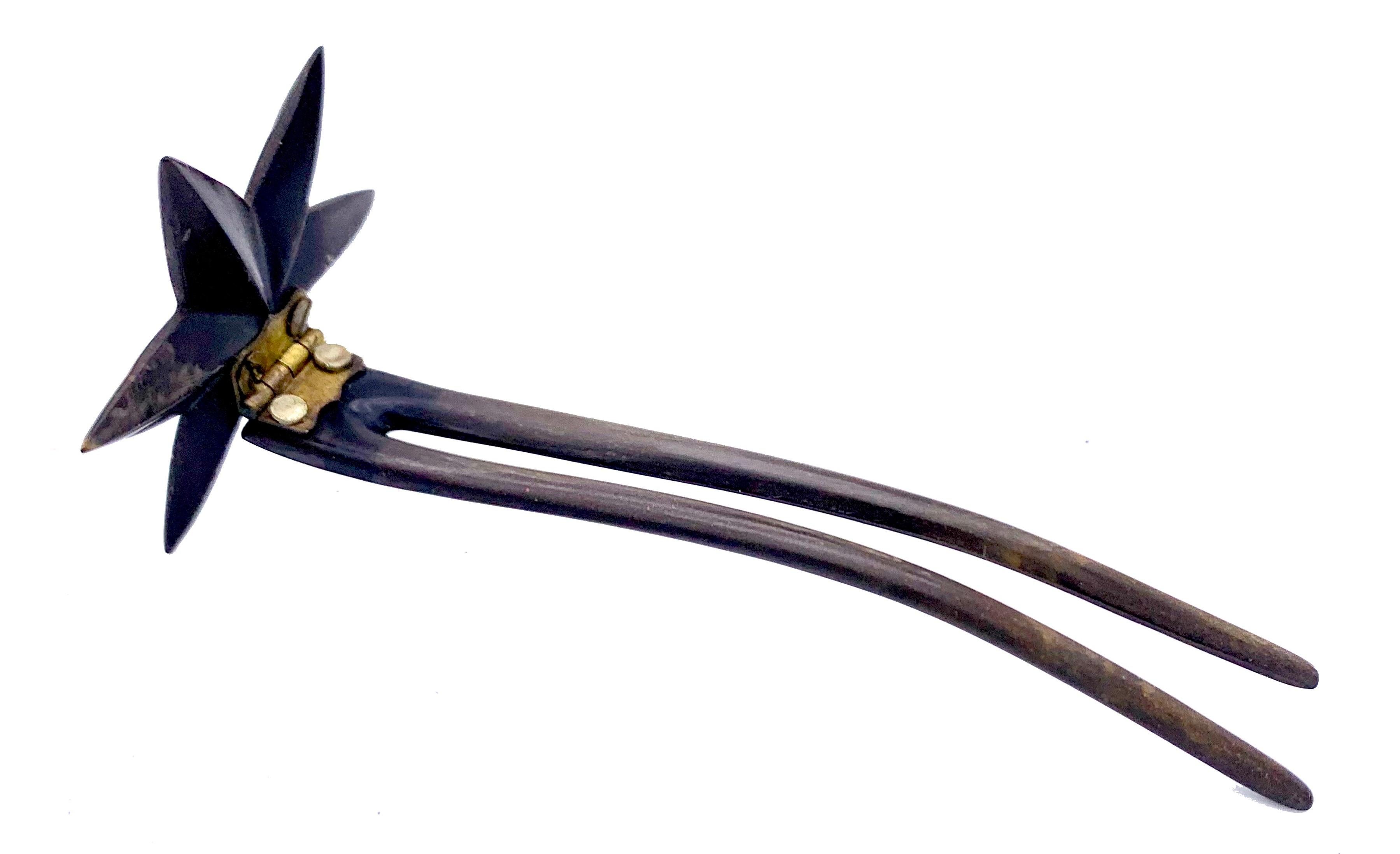 A vulcanite star is mounted onto a hair pin in made from the same material.
Vulcanite, also called gutta percha was made from rubber. 