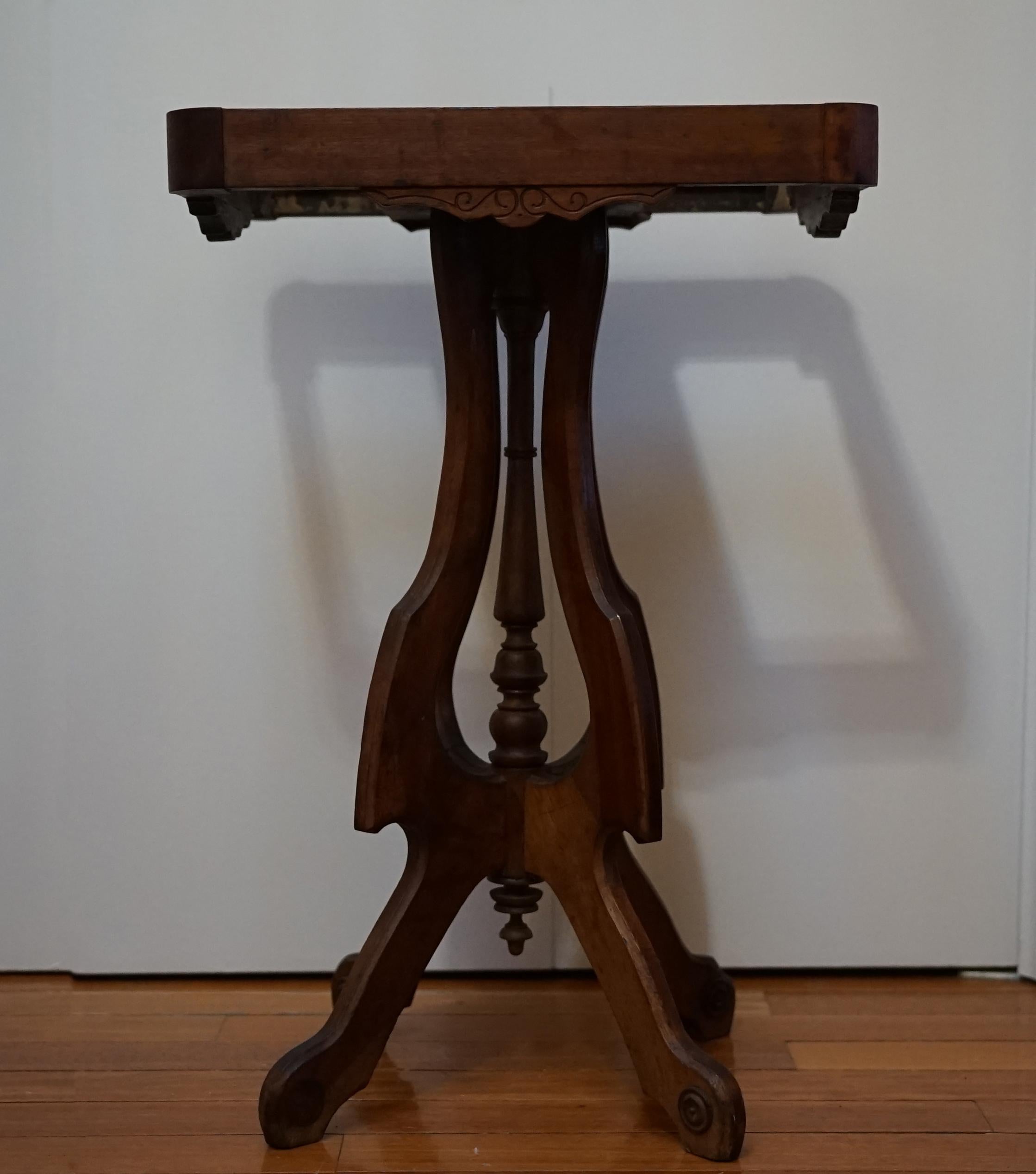 A rectangular white marble top rests on a walnut base with this occasional table. It is from the Victorian period. The carved walnut marble-topped table is 
American or English, and it was manufactured in 1881, according to a label that describes