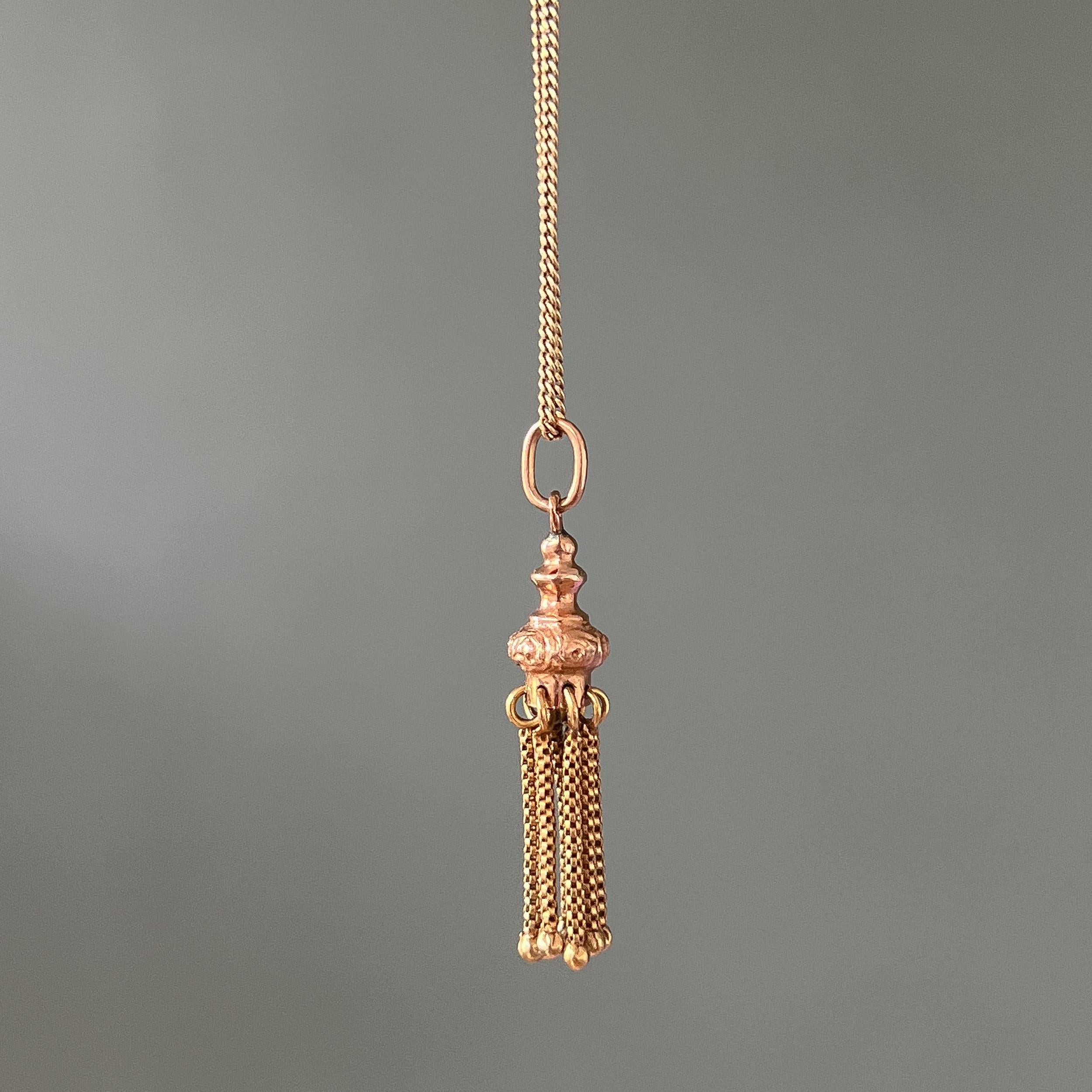 An antique Victorian 1890's tassel charm pendant made in 14 karat yellow gold. On top, the pendant is detailed with an Arabic dome decor and the eight Venetian tassel chains below are each hung on gold rings. The end caps of the tassels are set with