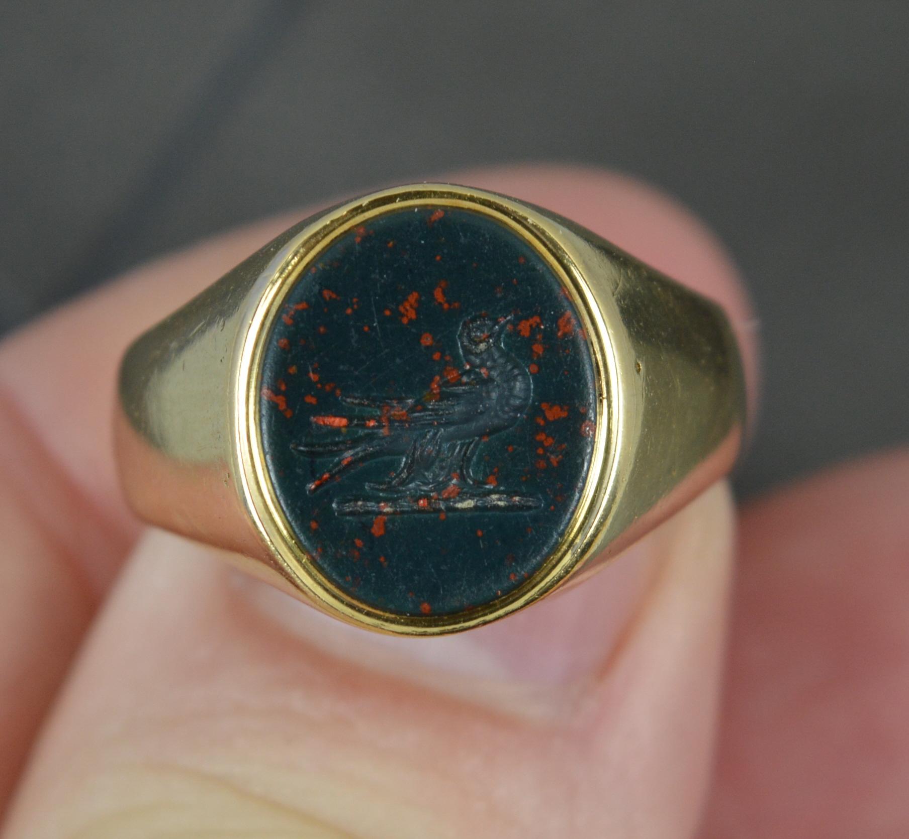 A superb antique signet ring.
Solid 18 carat yellow gold example.
Set with a single, oval shaped bloodstone to centre. 10.3mm x 12.3mm stone. Hand carved intaglio to depict a resting bird, looks to be the dove of peace.

CONDITION ; Very good. Clean