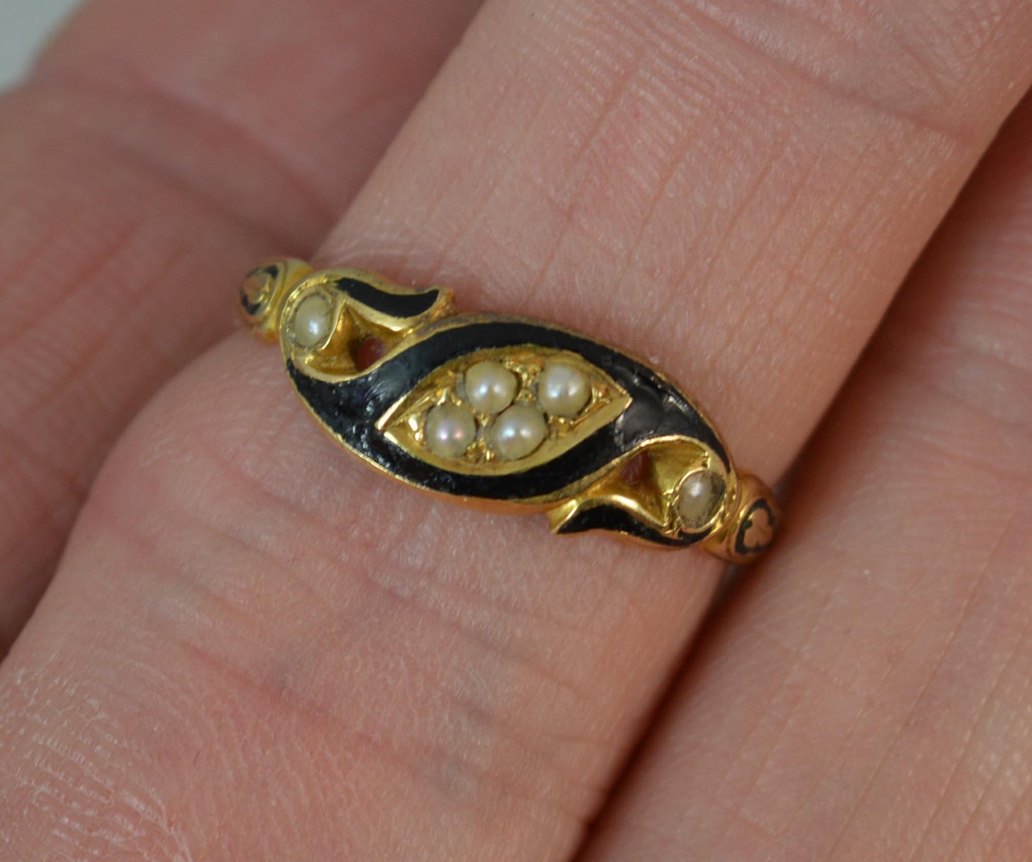 A mid Victorian period mourning ring, circa 1860/70.
18 carat yellow gold example.
Designed with four seed pearls to centre of a black enamel border and further pearl to each side.
6.5mm wide band to the front.

CONDITION ; Good for age. Clean band,