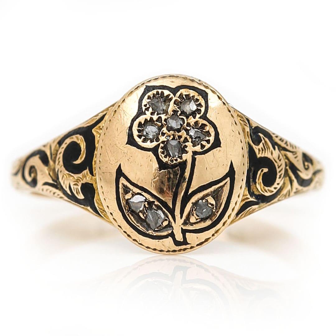 Une très jolie bague de deuil victorienne en or jaune 18ct, diamant taillé en rose et émail noir datant du milieu du 19ème siècle vers 1869. L'anneau de deuil représente l'un des symboles les plus courants de l'époque, la fleur de myosotis. Le