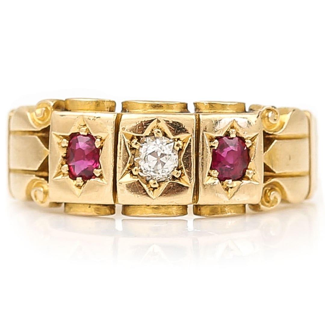 Dating from the late Victorian era this wonderful 18ct yellow band ring is set with a central old mine cut diamond and flanked by two oval cut pinkish rubies. The scroll work to the head and shank of the ring is in excellent condition retaining most