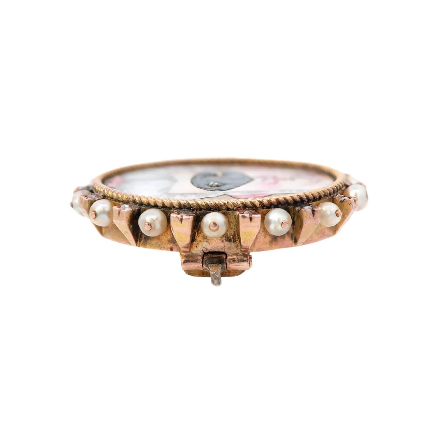 A beautiful enameled pin/pendant from the Victorian (ca1880) era! Made of 18kt yellow gold, this gorgeous pin features a round gold disk, which is surrounded by a braided wire border studded with pearls and rose cut diamonds. On the surface of the