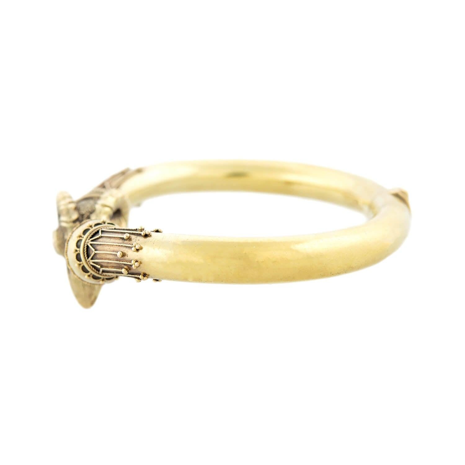An impressive statement bracelet from the Victorian (ca1890) era! Crafted in 18kt gold, the bangle incorporates a realistic ram's head motif into a stylish Etruscan design. Each 3-dimensional ram's head is incredibly detailed, including curling