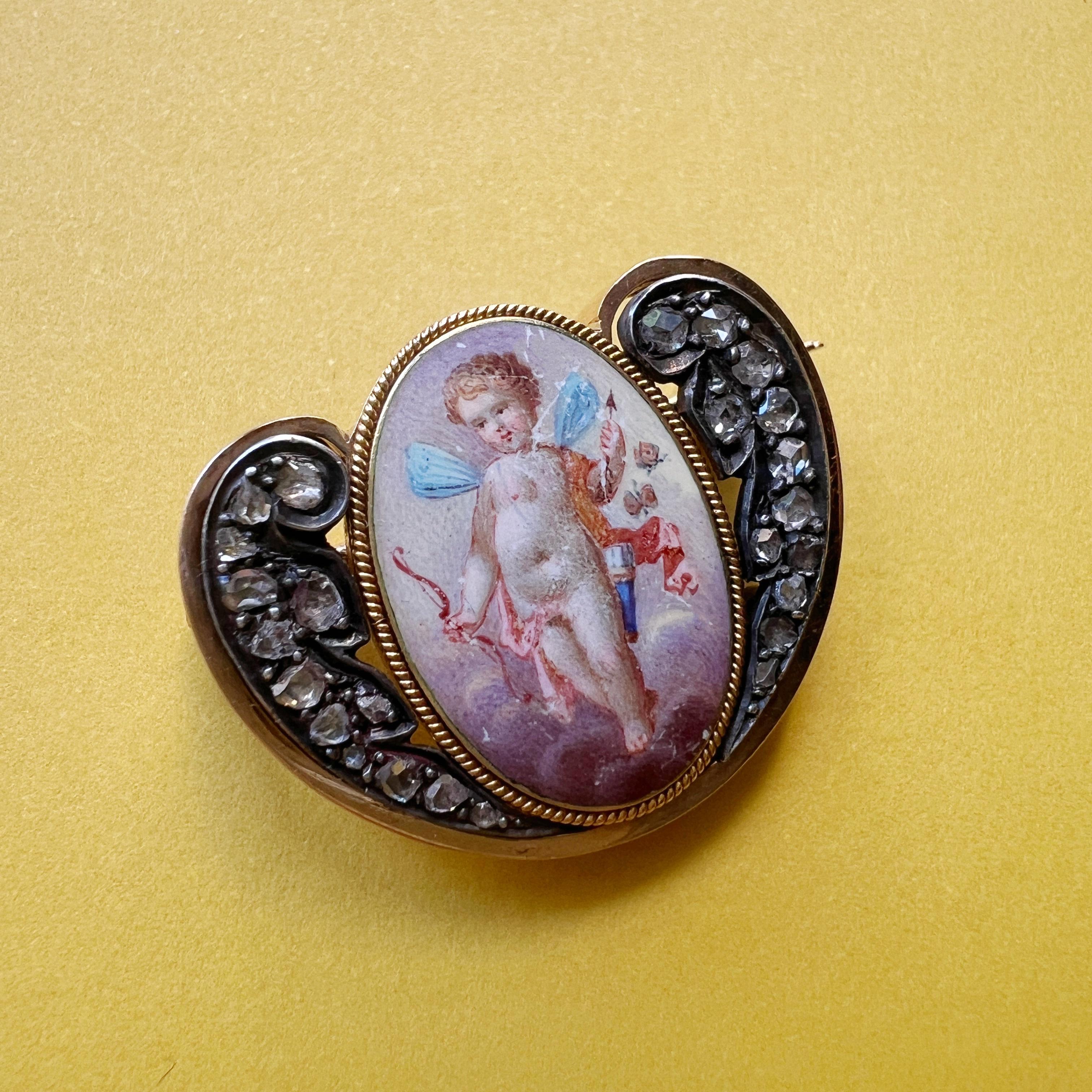 For sale a very sweet Victorian era 18K gold brooch featuring a cupid with delicate blue butterfly wings. The cupid, adorned in intricate details, holds an arrow poised for love and an arch, his tender gaze fixed forward, perhaps anticipating the