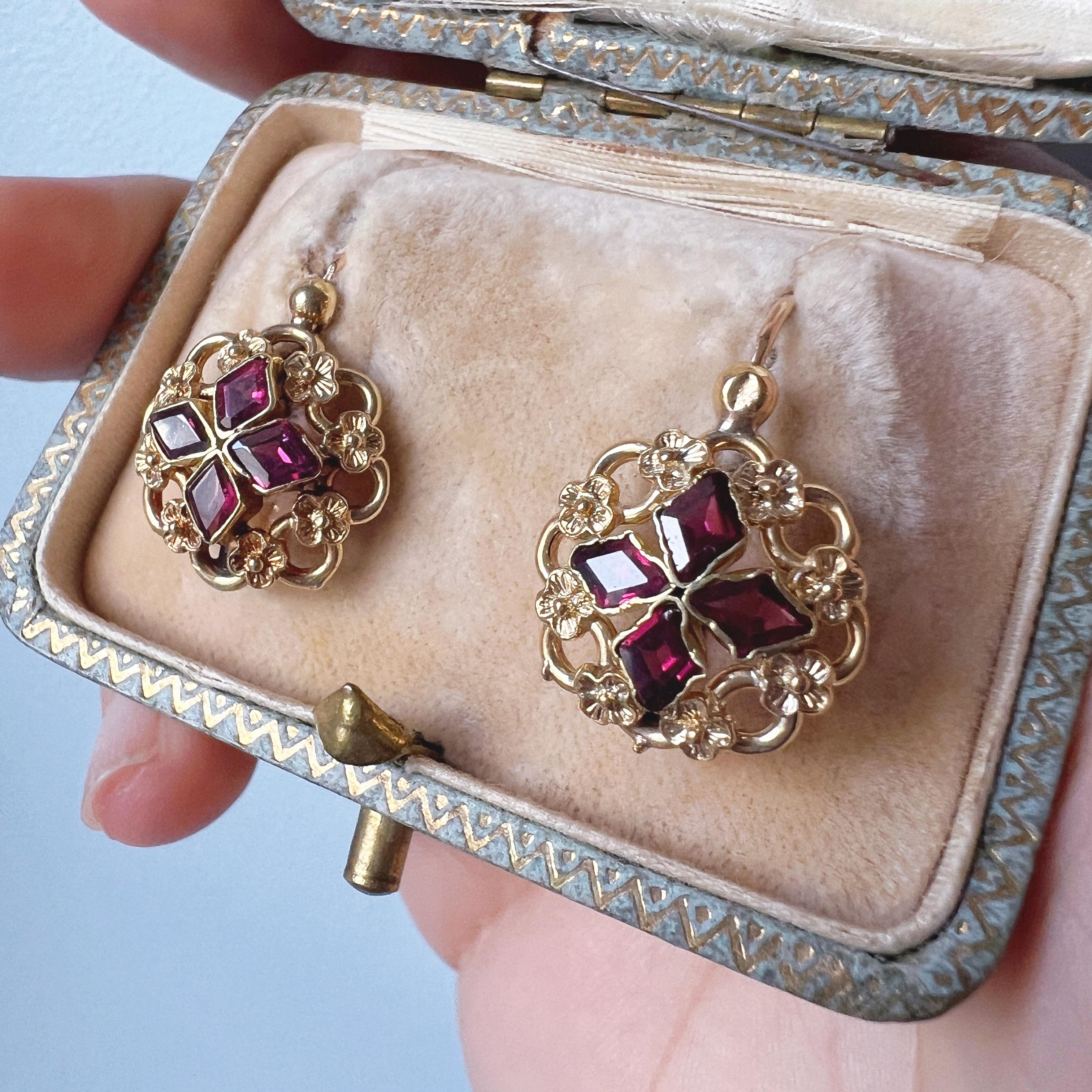 For sale a pair of enchanting 18K gold earrings from the Victorian era.

Each earring features a symmetrical arrangement of 4 flat cut, lozenge-shaped garnets on each side, artfully surrounded by 8 delicate golden flowers.

The juxtaposition of the