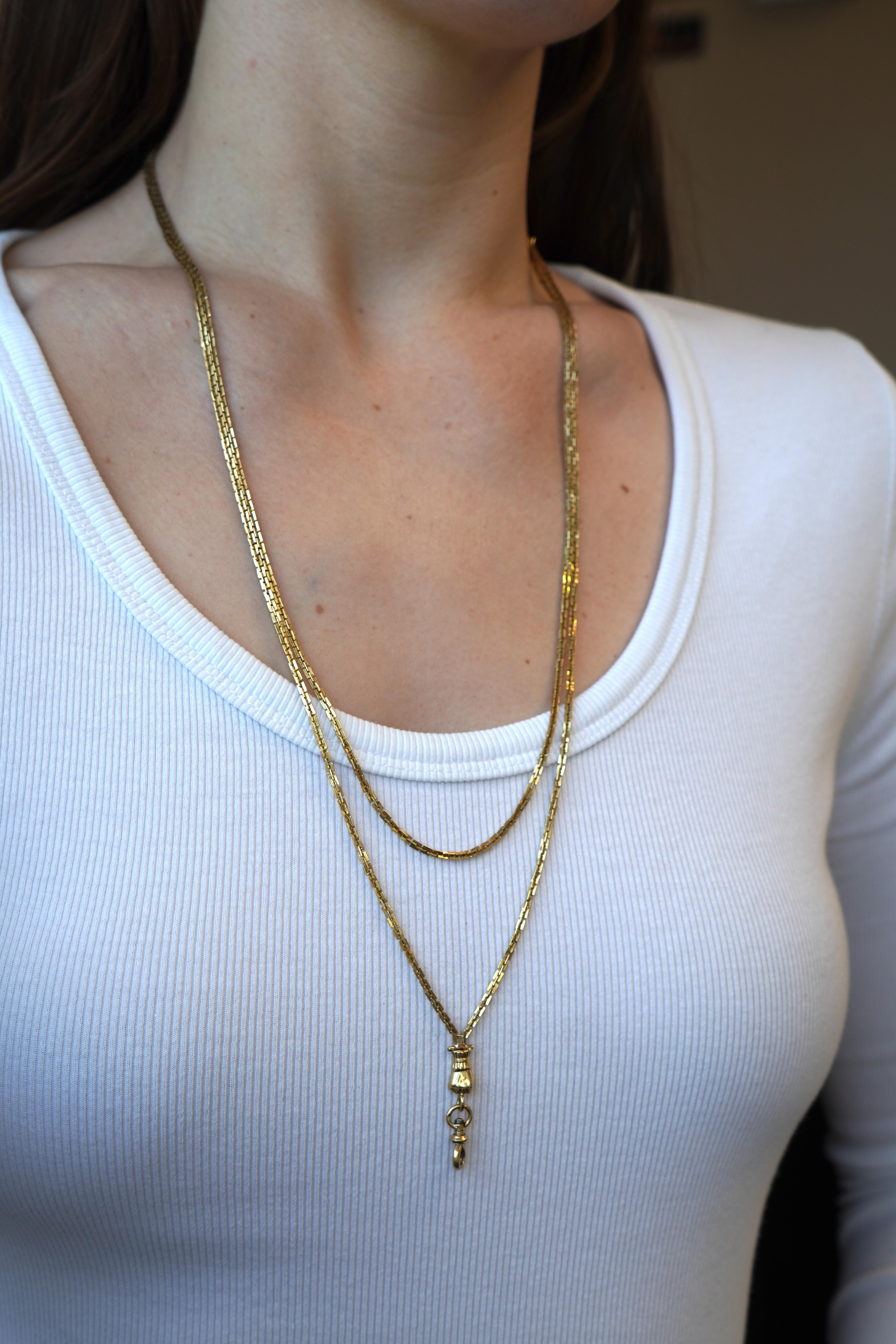 This antique French Victorian watch chain necklace is crafted in solid 18k yellow gold and features a classic long chain design. Measuring 53 inches in length, the chain offers versatility and can be worn doubled for a layered look. The necklace