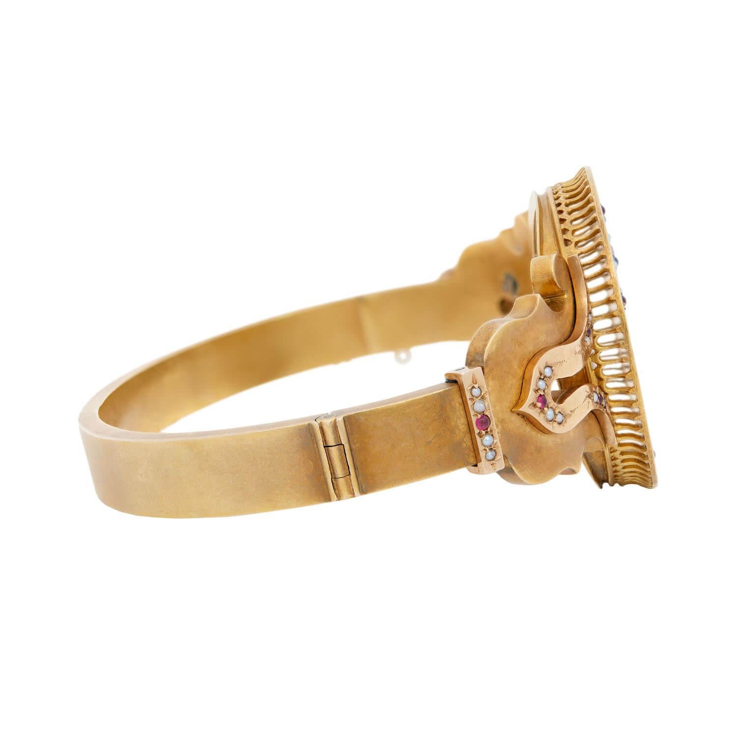 An unusual padlock bracelet from the Victorian (ca1880) era! This stylish bangle bracelet is made of 18k vibrant yellow gold, and features a circular centerpiece at the front detailed with intricate enamel and engraving. The centerpiece is decorated