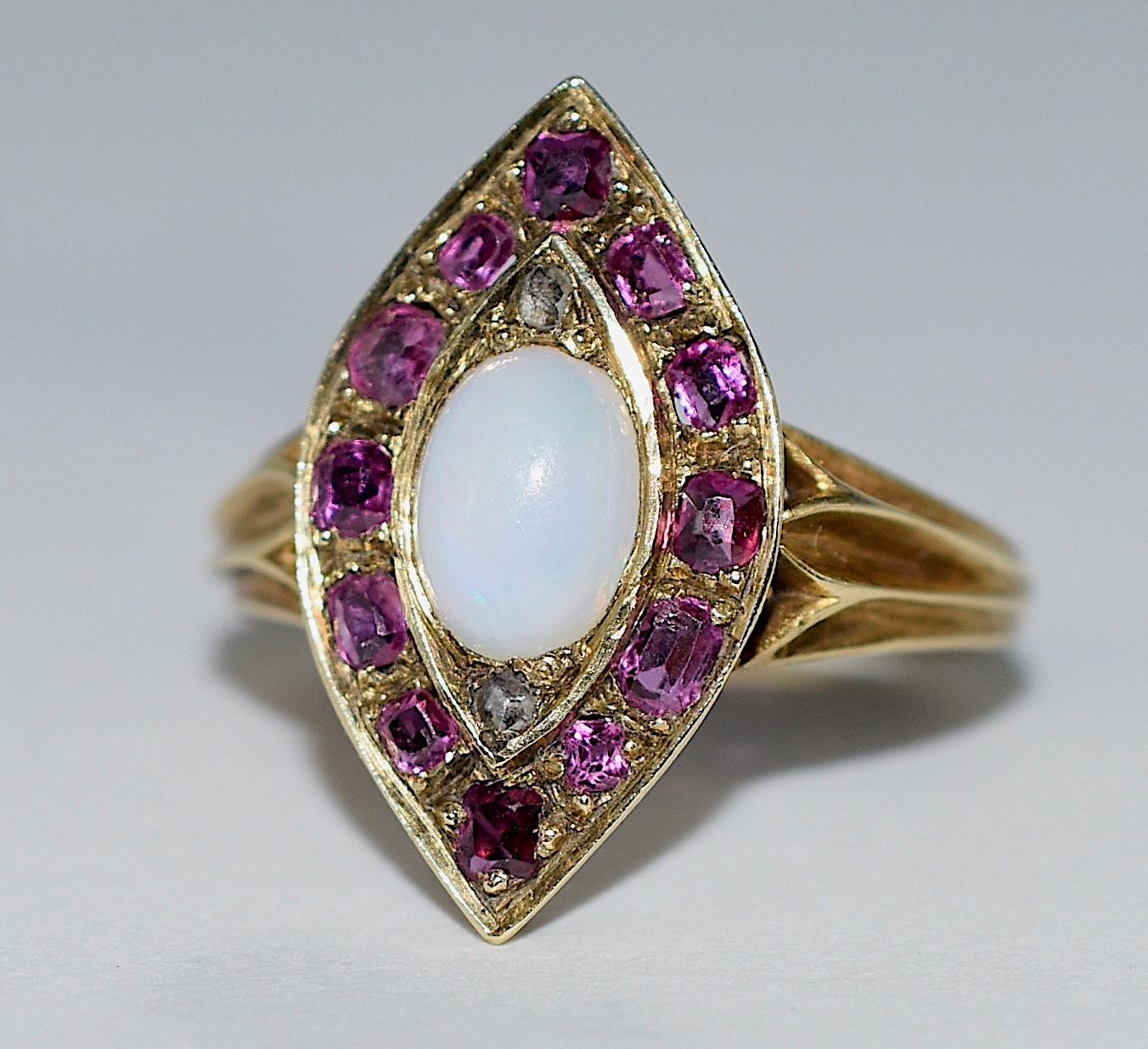 Our marquis shaped 18K ring, emblematic of the gothic arch, has twelve channel set old-cut rubies and a central cabochon opal accented with rose diamonds at each pointed arch. The ring is a 