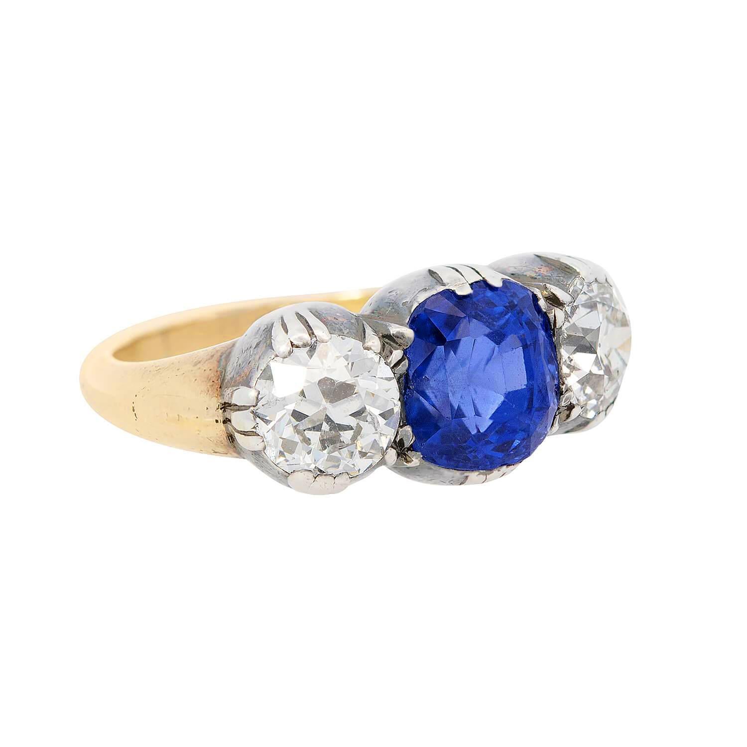 Un sorprendente anello a tre pietre con zaffiro e diamante di epoca vittoriana (ca. 1880)! Realizzato in oro giallo 18 carati e argento sterling, questo incredibile anello presenta un bellissimo zaffiro blu affiancato da due grandi diamanti in una