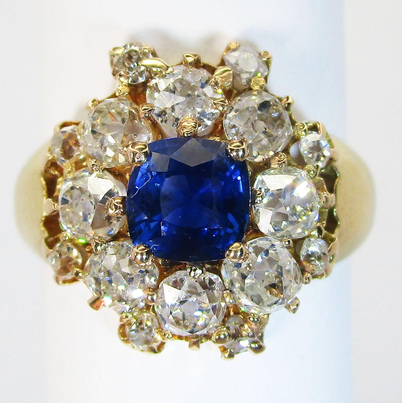 This ring boasts a brilliant, deep blue natural colored sapphire at its center that is nearly one carat! The center stone is cushion cut and such a rich blue that even in soft evening light, it boasts royal blue depth! The sapphire is surrounded by