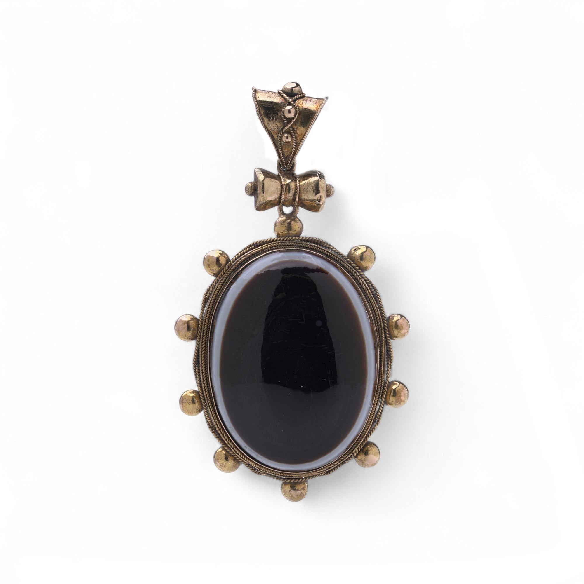 Pendentif victorien en or jaune 18 carats. La pièce est sertie d'un grand cabochon ovale en agate, encadré par des perles d'or et des détails en fil de fer, avec un nœud orné et une anse de forme triangulaire.

Dimensions -
Poids : 31,41 g
Longueur