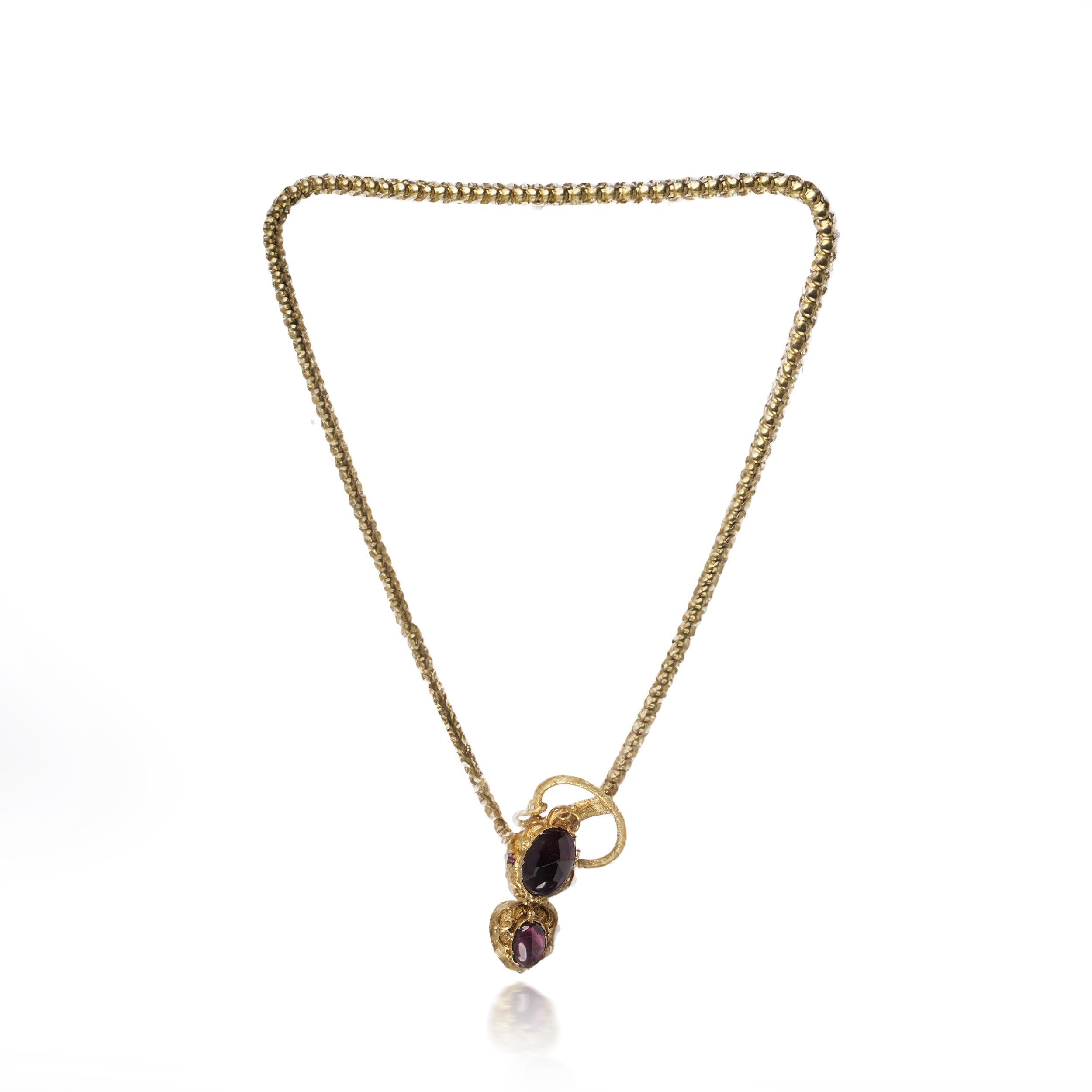 A sentimental jewel featuring a symbolic serpent motif and a hairwork locket.

Victorian necklace in 18 karat yellow gold, composed of a finely detailed snake chain terminating in an entwined serpent head clasp. The textured snake is set with a
