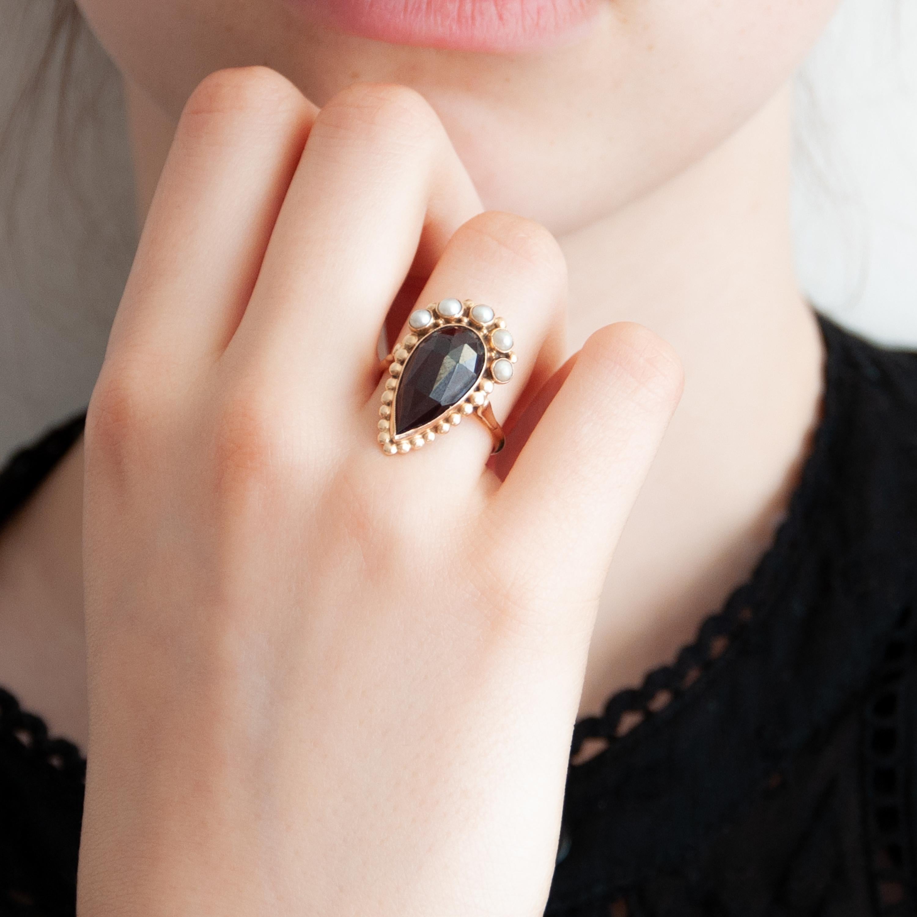 This drop-shaped facet garnet ring featuring five clear seed pearls. The garnet is set in a 14 karat gold frame crowned with lustrous pearls. This ring showcases a deep red garnet and is simply delightful.

The gold has the Dutch purity hallmark,