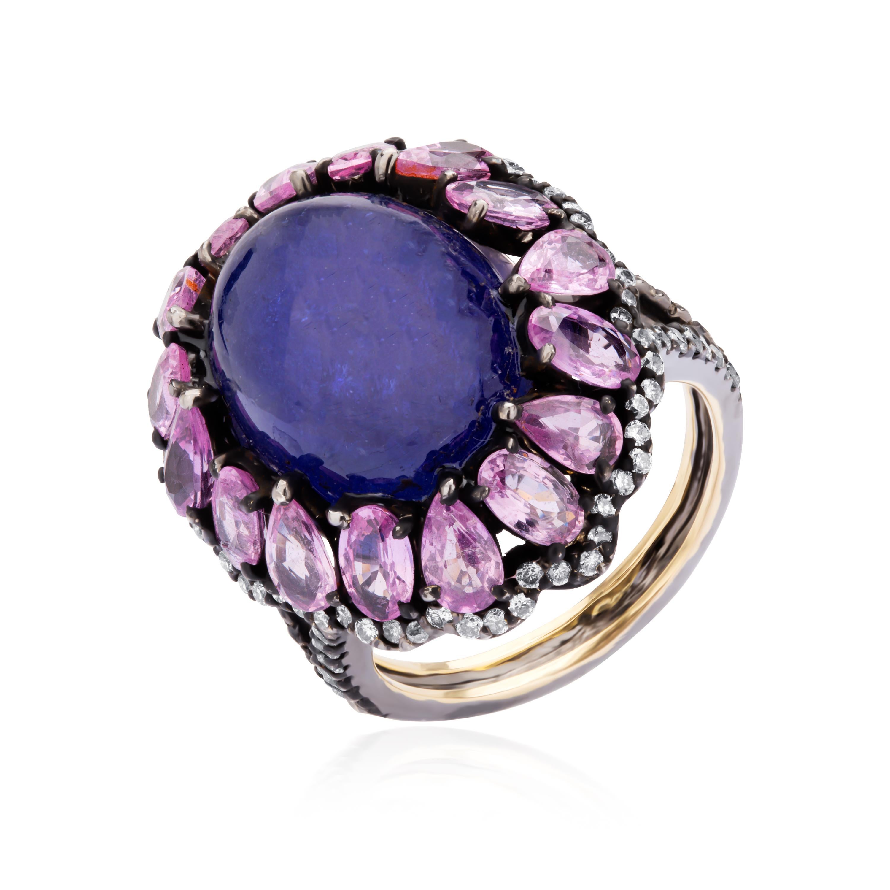 Vividly colorful, this gorgeous Victorian ring gleams with a stupendous 12*15 mm cabochon of 14. 5 carat Tanzanite sitting amidst a sparkling pool of faceted oval and pear cut pink sapphires alternating with each other. The center design is