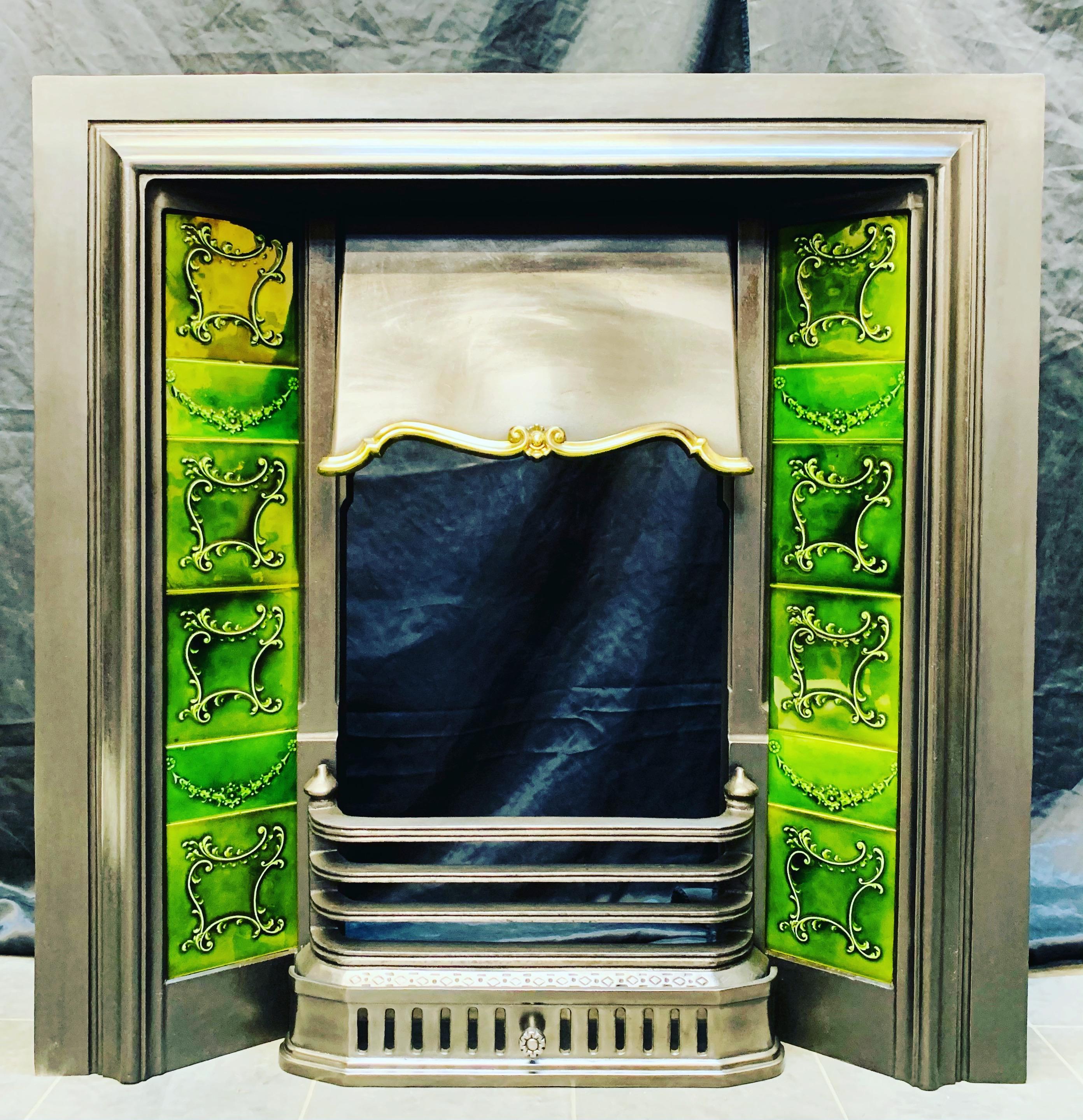 A late Victorian 19th century cast iron fireplace insert with attractive bottle green side tiles. A generous outer frame, with original bottle green side tiles, centred a shaped hood with brass cartouche embellishment, bellow a three barred fire