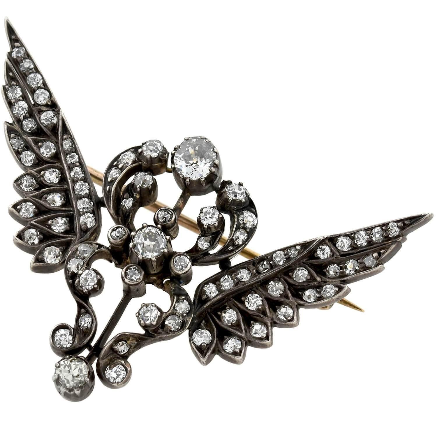 An absolutely stunning diamond wing pin from the Victorian (ca1880) era! This spectacular piece is crafted in 15kt rose gold topped in sterling silver and forms the shape of a fabulous open winged motif with an ornate center. Incredible old Mine Cut