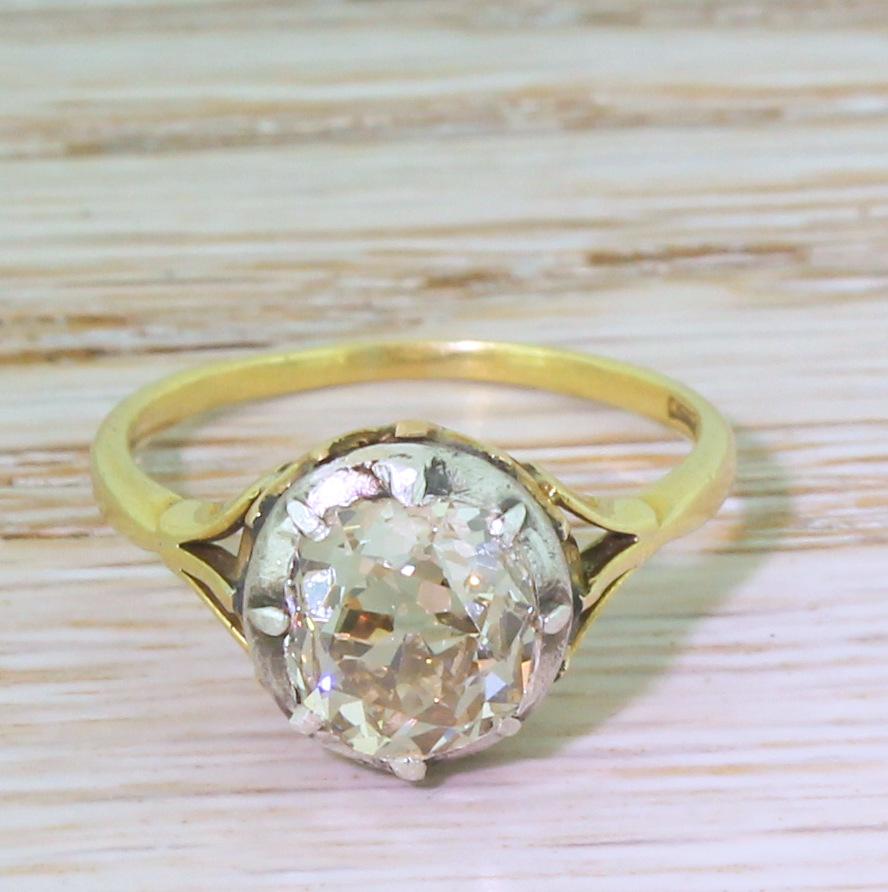 Wholly unique and utterly beautiful. The cushion shaped old cut diamond displays internally clean and displays a soft champagne hue. The diamond is secured in a cut-back silver setting which nestles in a 18k yellow gold collet. With tri-split