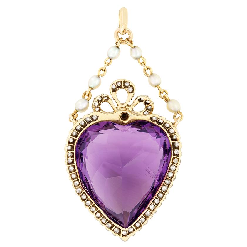 Una splendida ametista a forma di cuore da 24,00 carati è al centro di questo ciondolo vittoriano. Incastonata nell'argento, come si usava nel periodo vittoriano, l'ametista è circondata da un'aureola di diamanti di vecchio taglio, con un disegno a