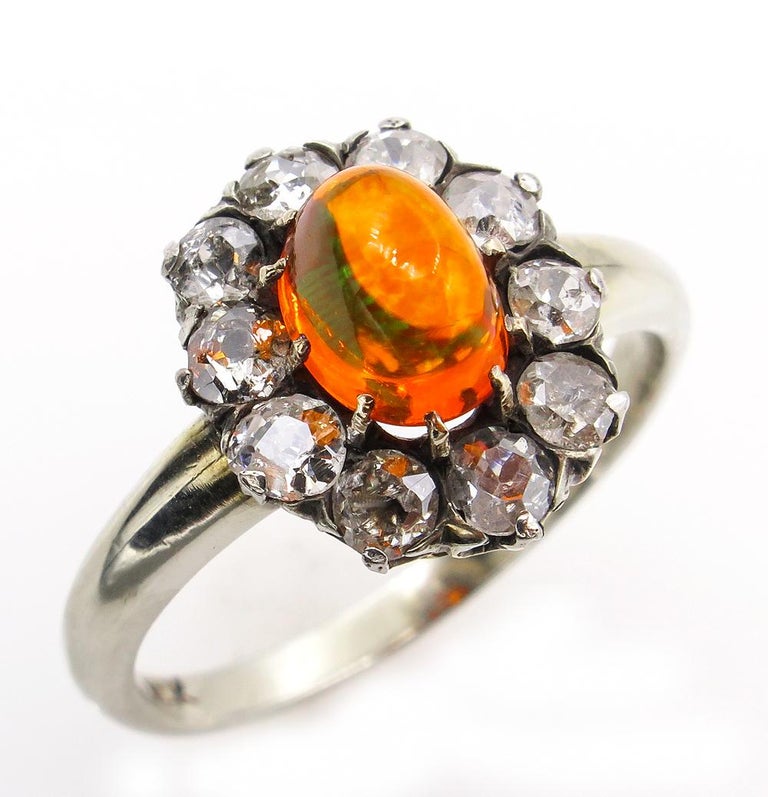 A Beautiful Authentic Classic VICTORIAN Cluster Flower shaped Ring with Fire Opal and Old Cut Diamonds in 14K White Gold topped with silver, create a hypnotic radiance and luster with a splash of color. CIRCA 1890s.
A Bright Fire Opal is estimated