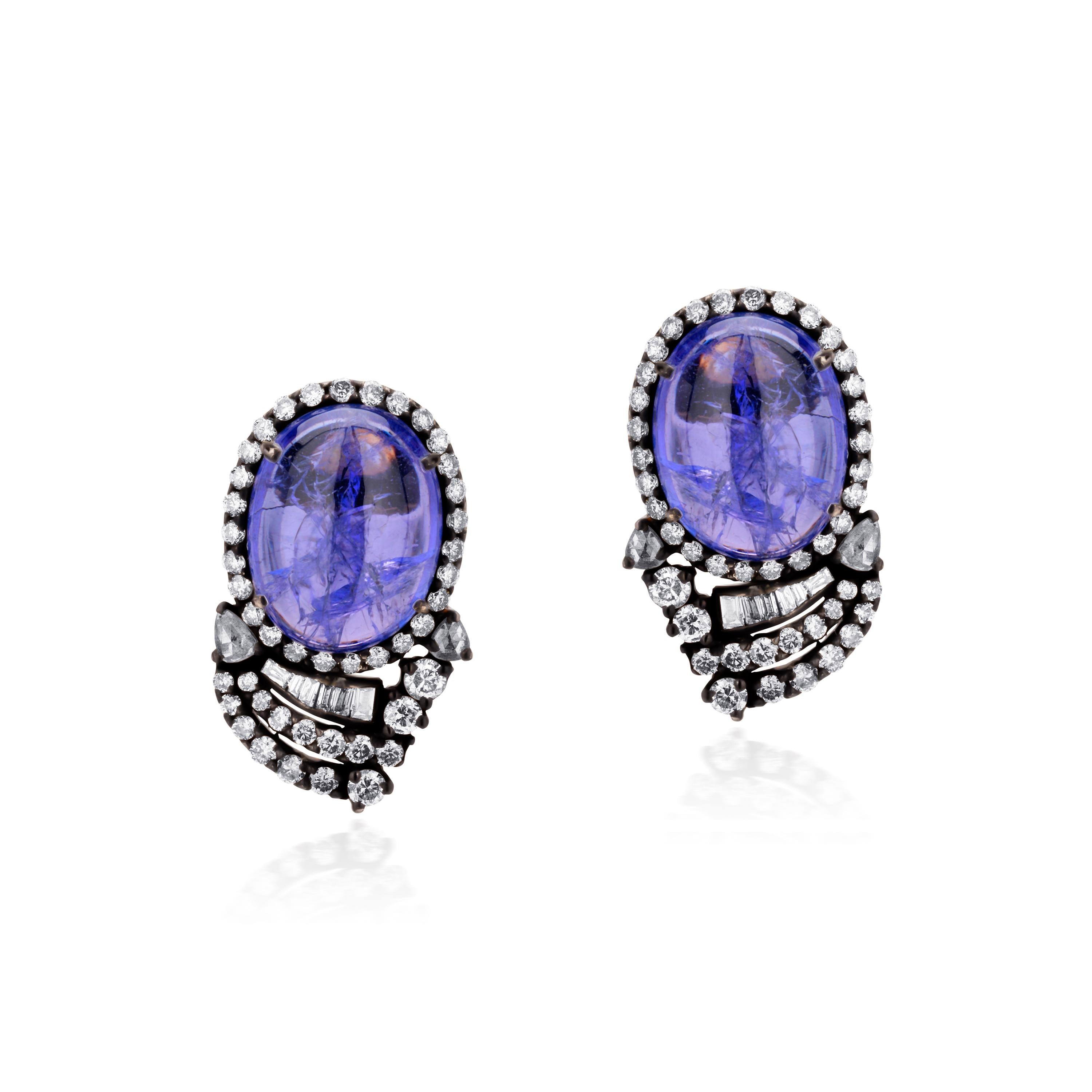 These Victorian studs are resplendent with two oval shaped tanzanite cabochons together weighing 22.5Cts. Each tanzanite is surrounded by sparkling round prong set diamonds mounted of black metal. The bottom of the stone has rows of diamonds in