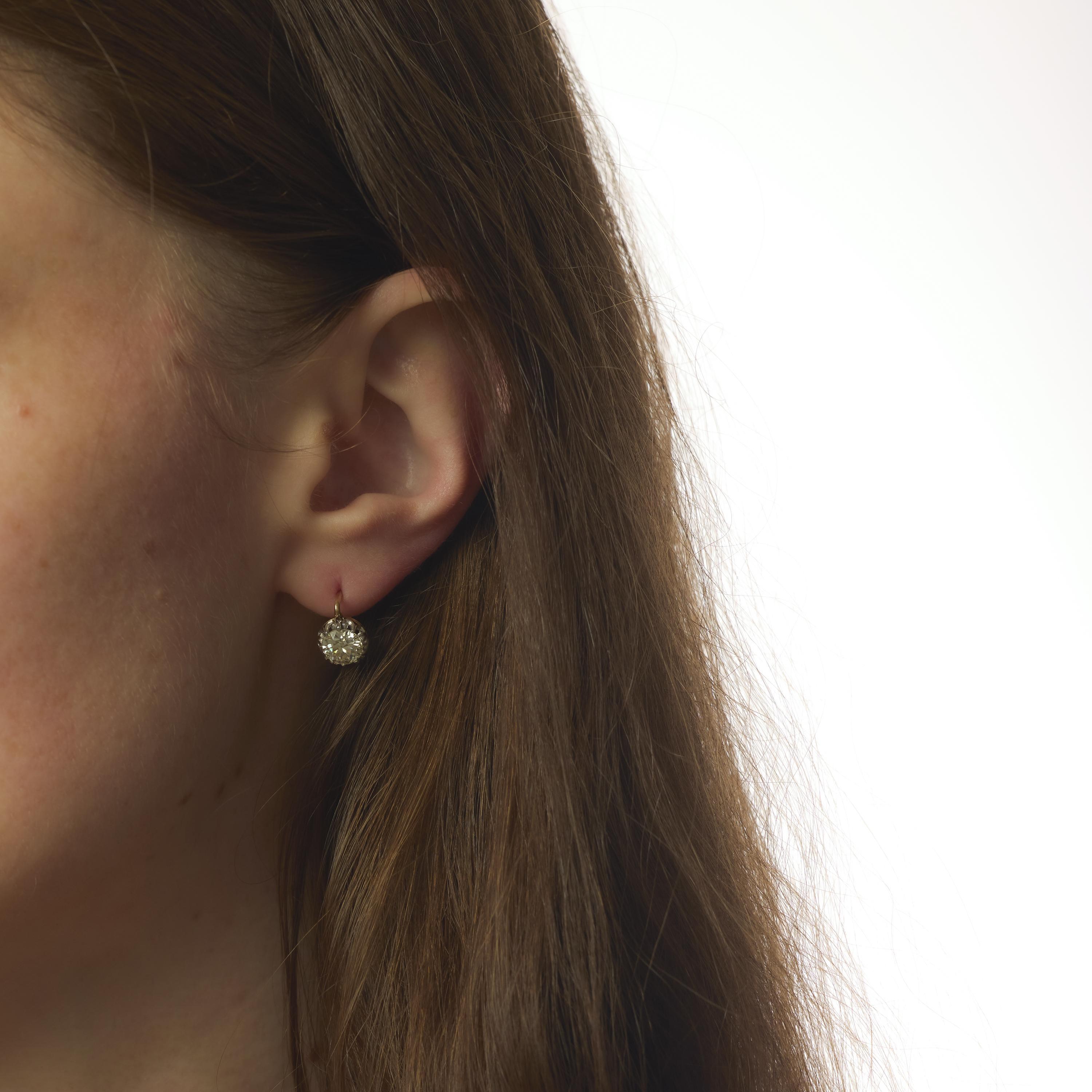 Ces boucles d'oreilles victoriennes des années 1880 présentent deux diamants de taille européenne ancienne totalisant environ 2,60 carats, d'une couleur chaude L-M et d'une clarté exceptionnelle VS. Les coupes anciennes rayonnent d'un doux éclat