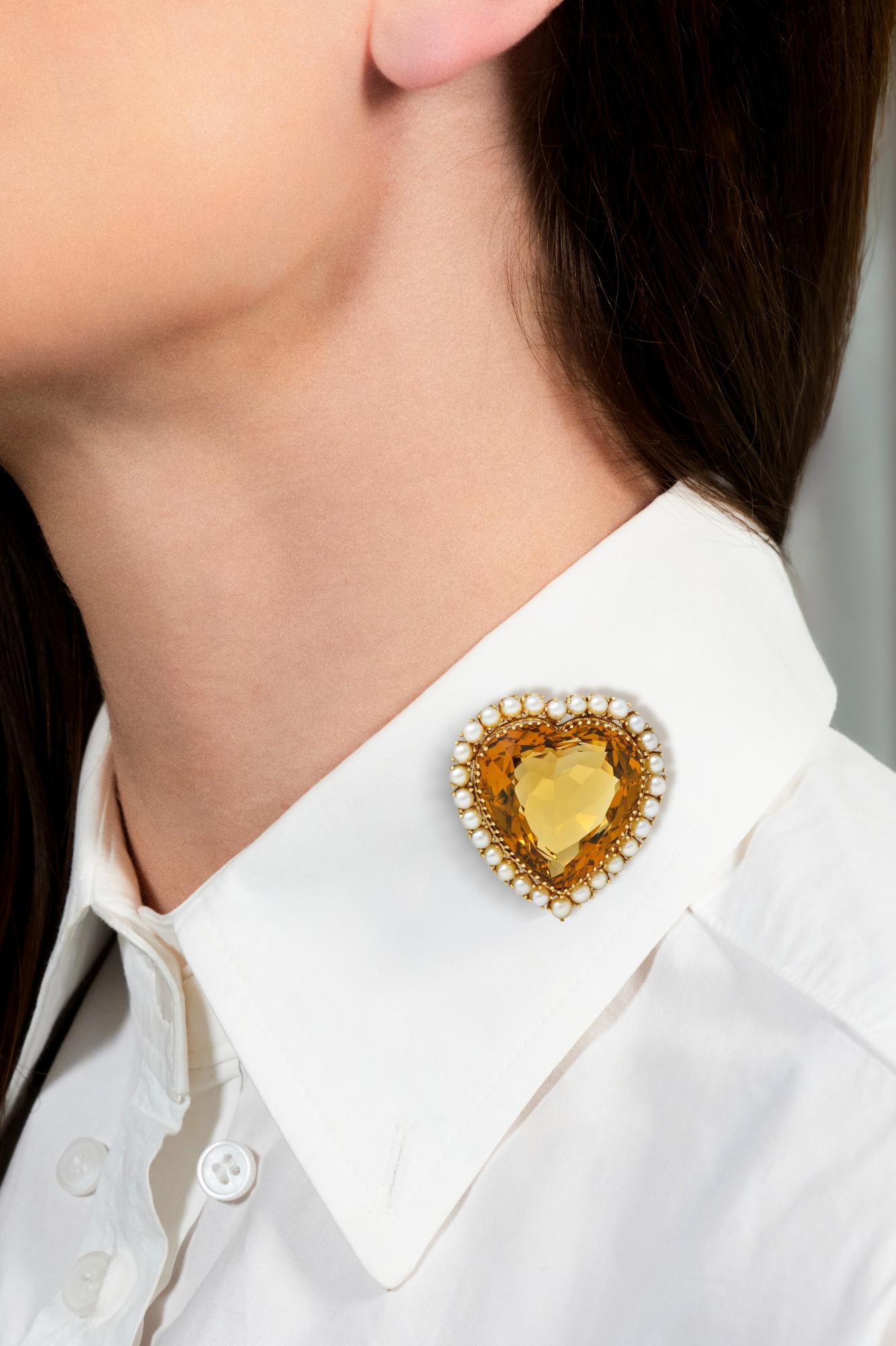 Au centre, une citrine taillée en cœur pesant environ 29,37 carats - orange brunâtre moyen transparent
Serti d'anneaux stylisés percés et d'un halo de perles serties.
Whiting de 3,0 à 5,0 mm de diamètre - blanc avec une forte iridescence
Complété