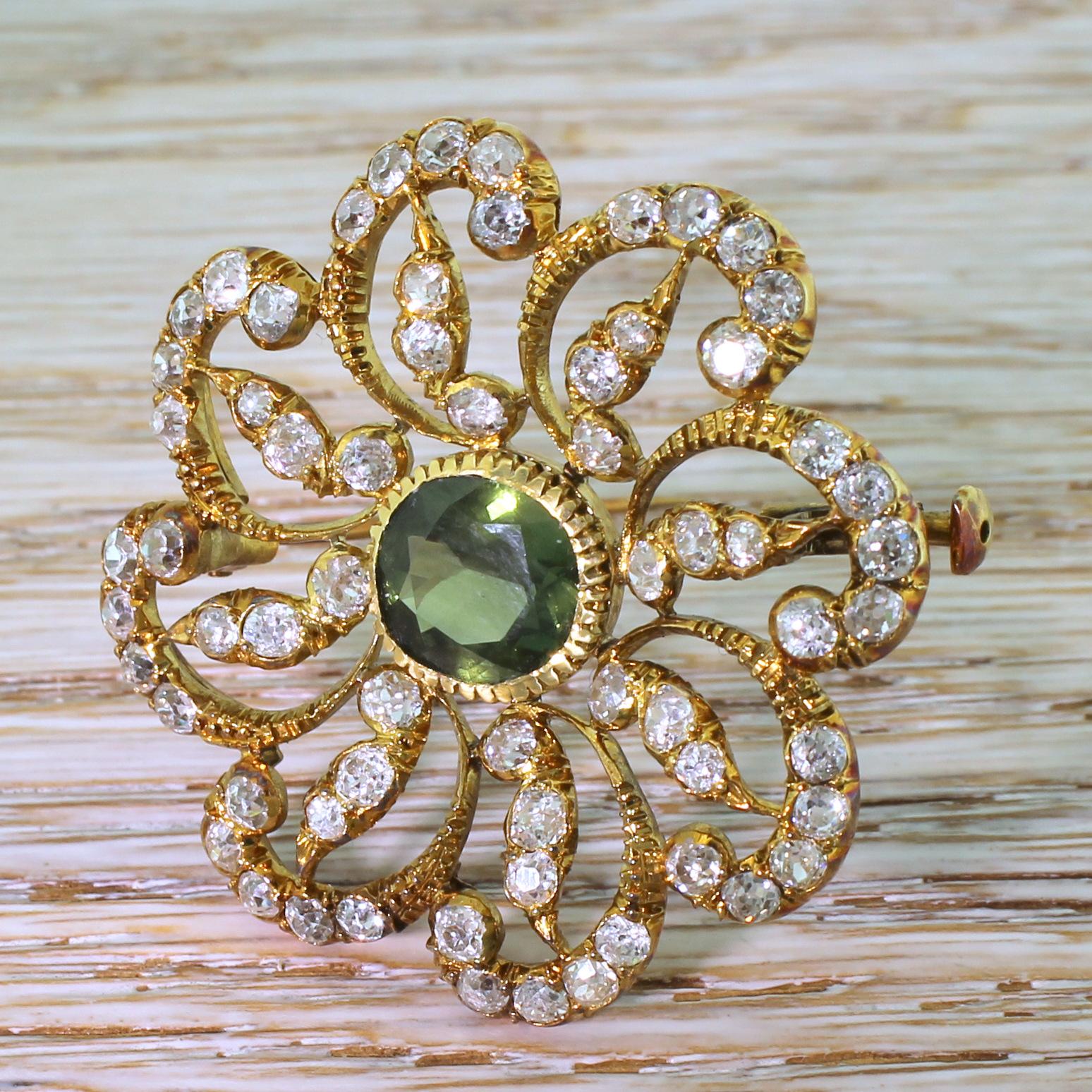 A wonderfully impressive Victorian brooch. Set at the centre is a slightly cushion shaped sapphire which displays a bright, olive-y green. The stunning, swirling surround is set with 64 white and bright old cut diamonds in finely grained yellow