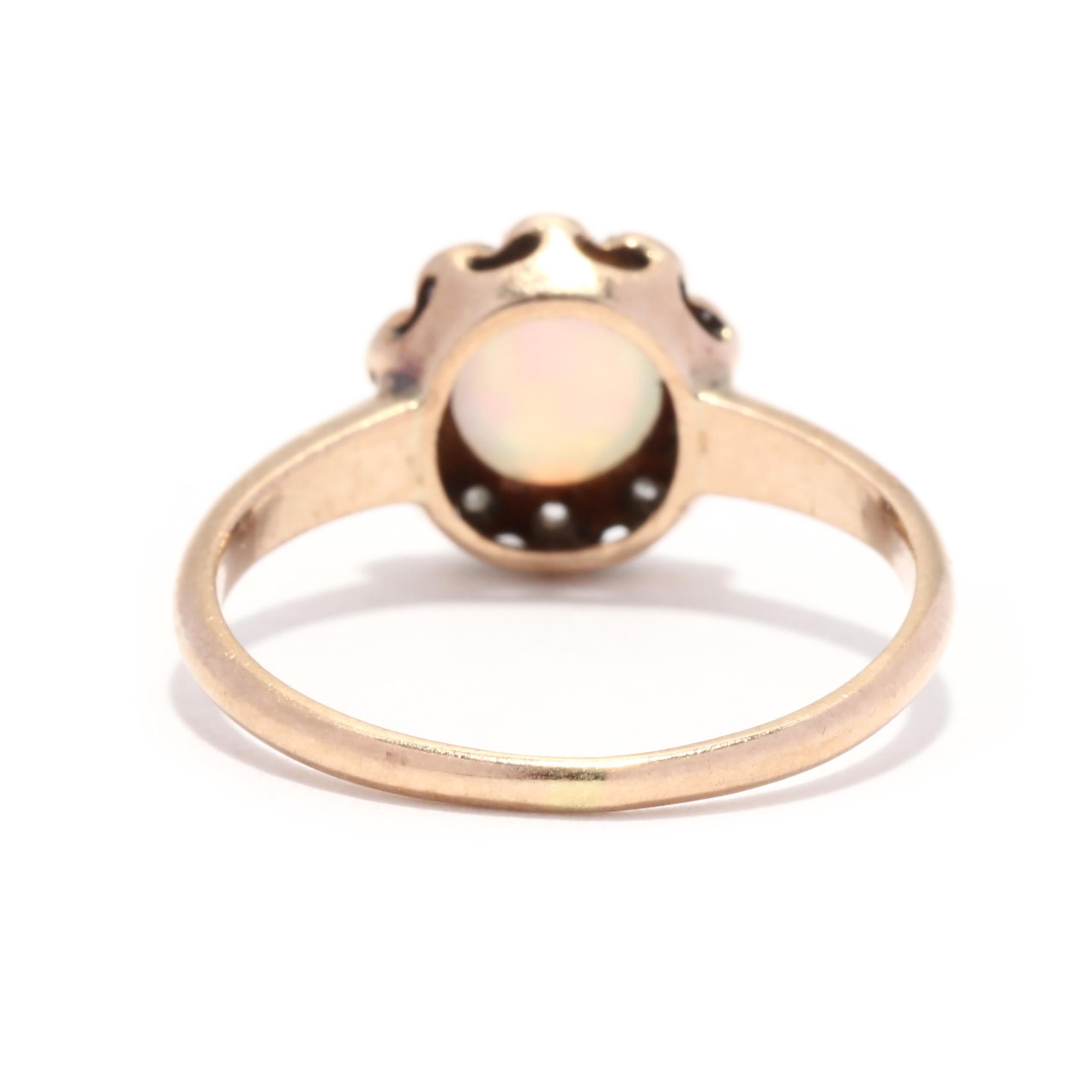 A Victorian 10 karat yellow gold opal and diamond ring. This antique ring features a round cabochon opal weighing approximately .27 carat surrounded by a single and old rose cut diamond halo weighing approximately .04 total carats and with a tapered