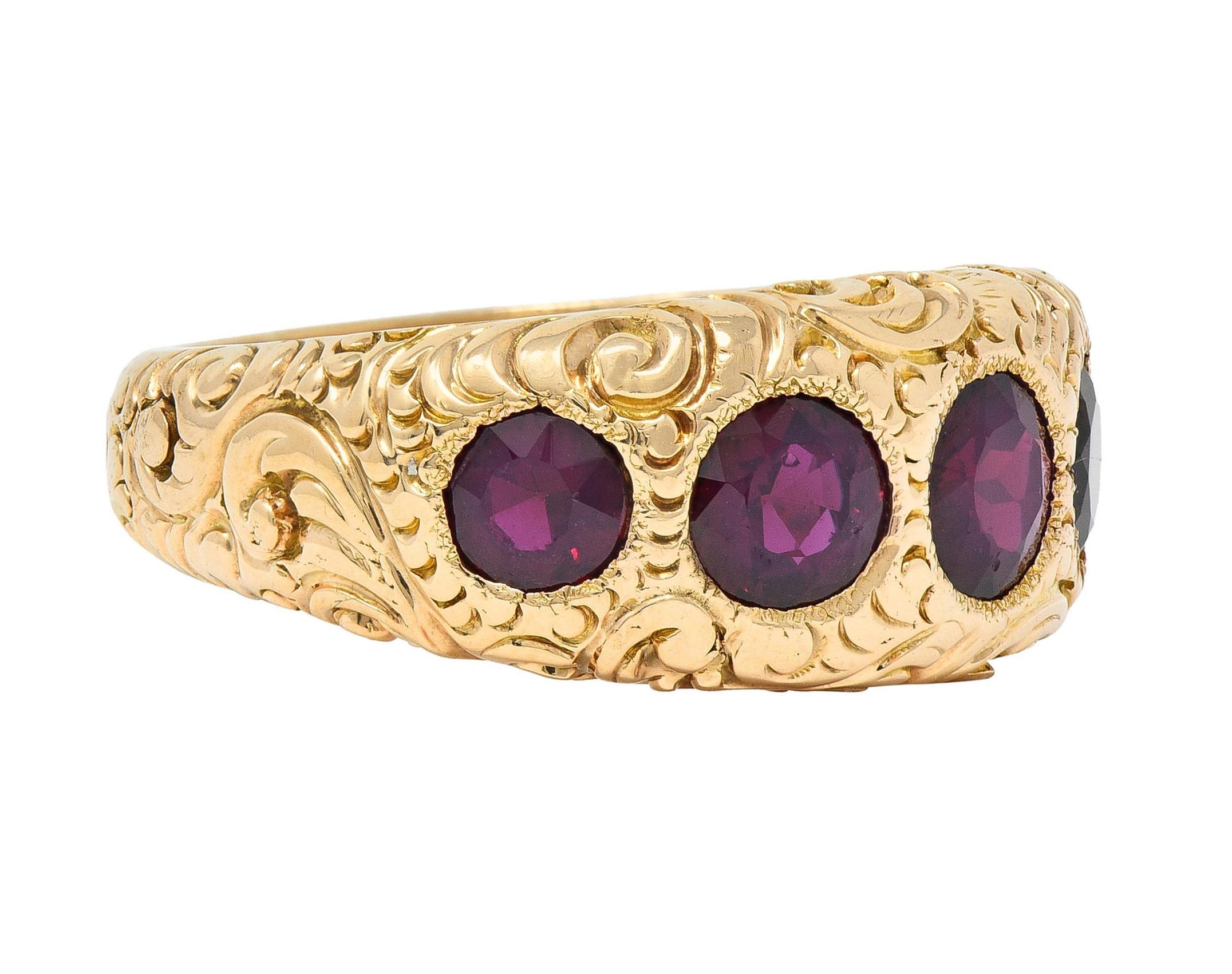 Centering five graduated round cut garnets flush set east to west
Transparent medium-dark red to orangey-red in color 
Weighing approximately 3.44 carats total 
With an engraved scroll motif surround 
Stamped for 14 karat gold
Circa: 1860s
Ring
