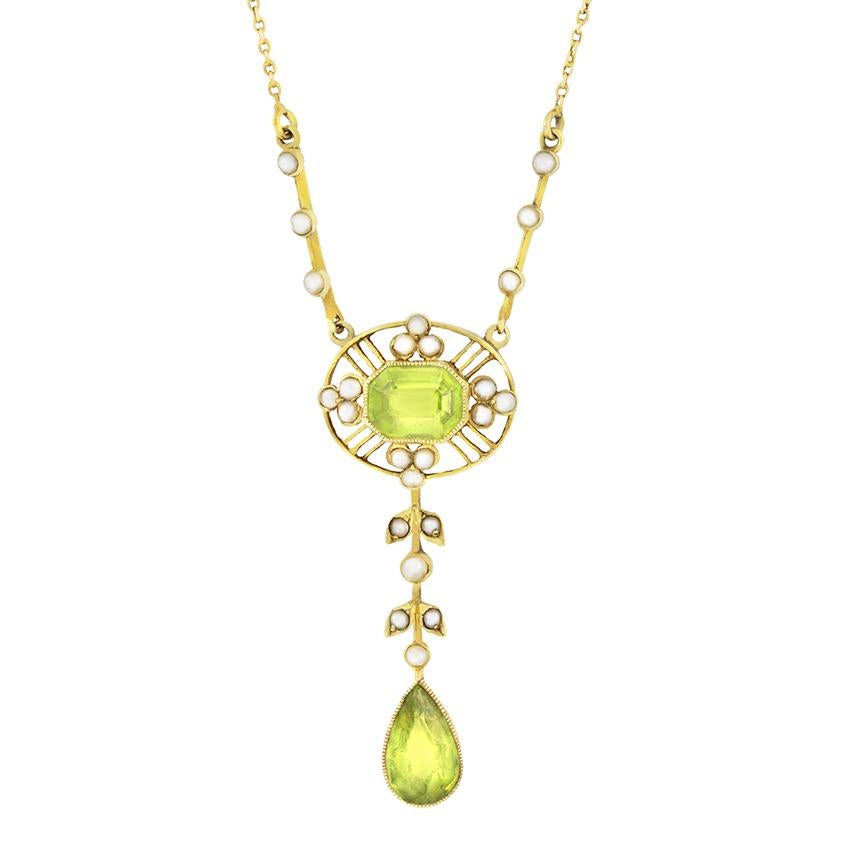 Diese wunderschöne Halskette aus der viktorianischen Ära wurde in Handarbeit aus 15 Karat Gelbgold gefertigt. In der Mitte befindet sich ein auffälliger Peridot im Smaragdschliff von 2,00 Karat, der von Halbmeeresperlen umrahmt ist. Ein anmutiger