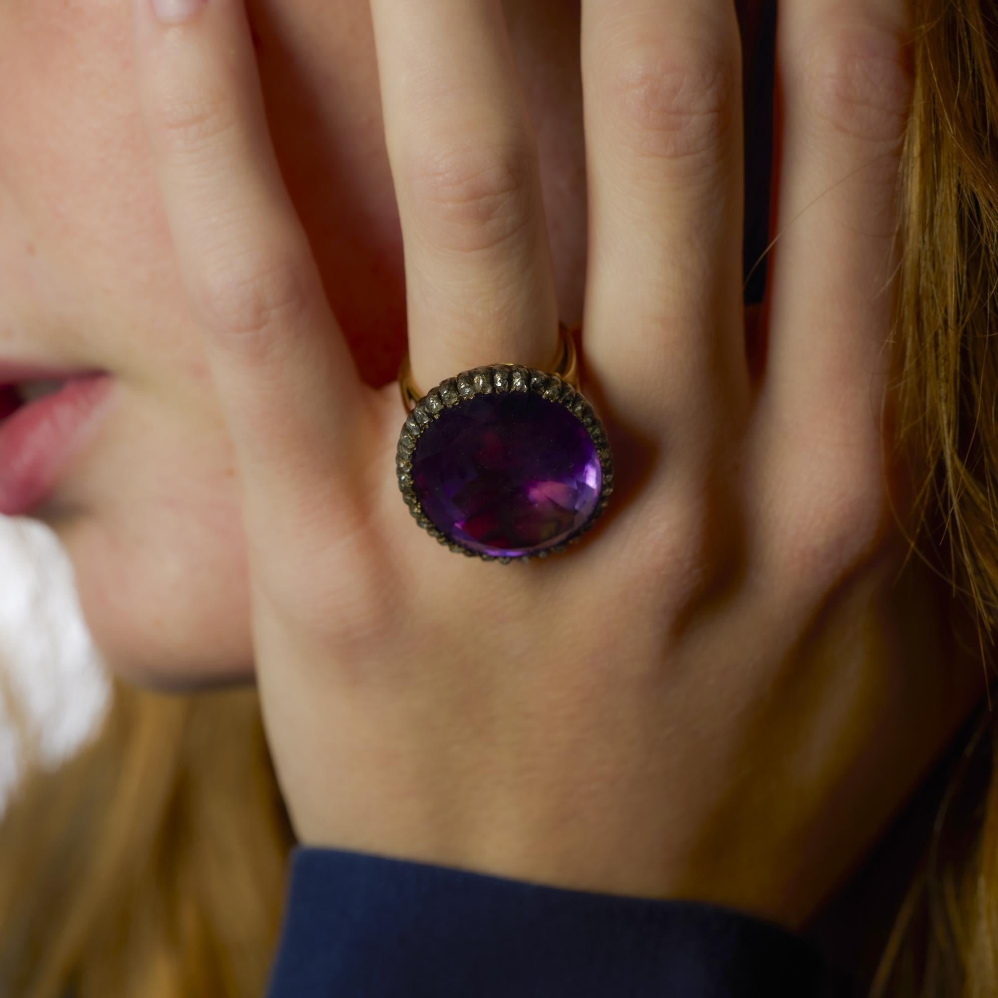 Questo anello vittoriano in oro giallo 18 carati e argento presenta una straordinaria ametista da 37 carati incorniciata da diamanti antichi taglio rosa in una silhouette audace e storica.