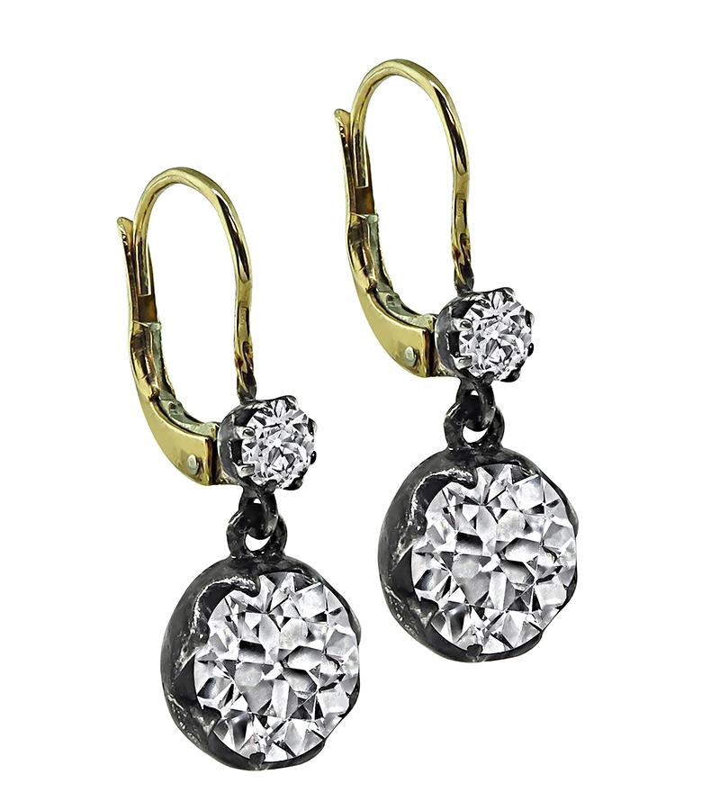 This is a stunning pair of silver and gold earrings. The earrings feature sparkling 2 large old mine cut diamonds that weigh approximately 3.82ct. The color of these diamonds is J-K with VS2 clarity. The two large diamonds are accentuated by two
