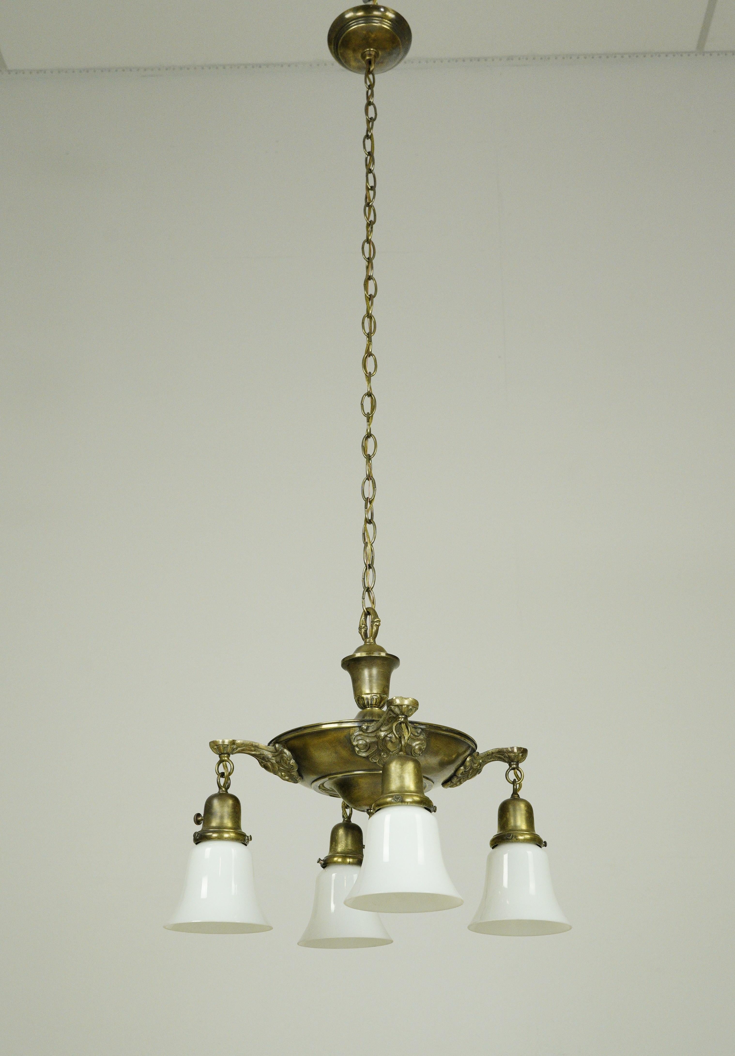 Lampadario a padella in stile vittoriano con quattro paralumi bianchi, una struttura a padella ornata in ottone antico e una catena in acciaio di nuova fabbricazione. Richiede quattro lampadine standard a base media. Questa luce è stata restaurata