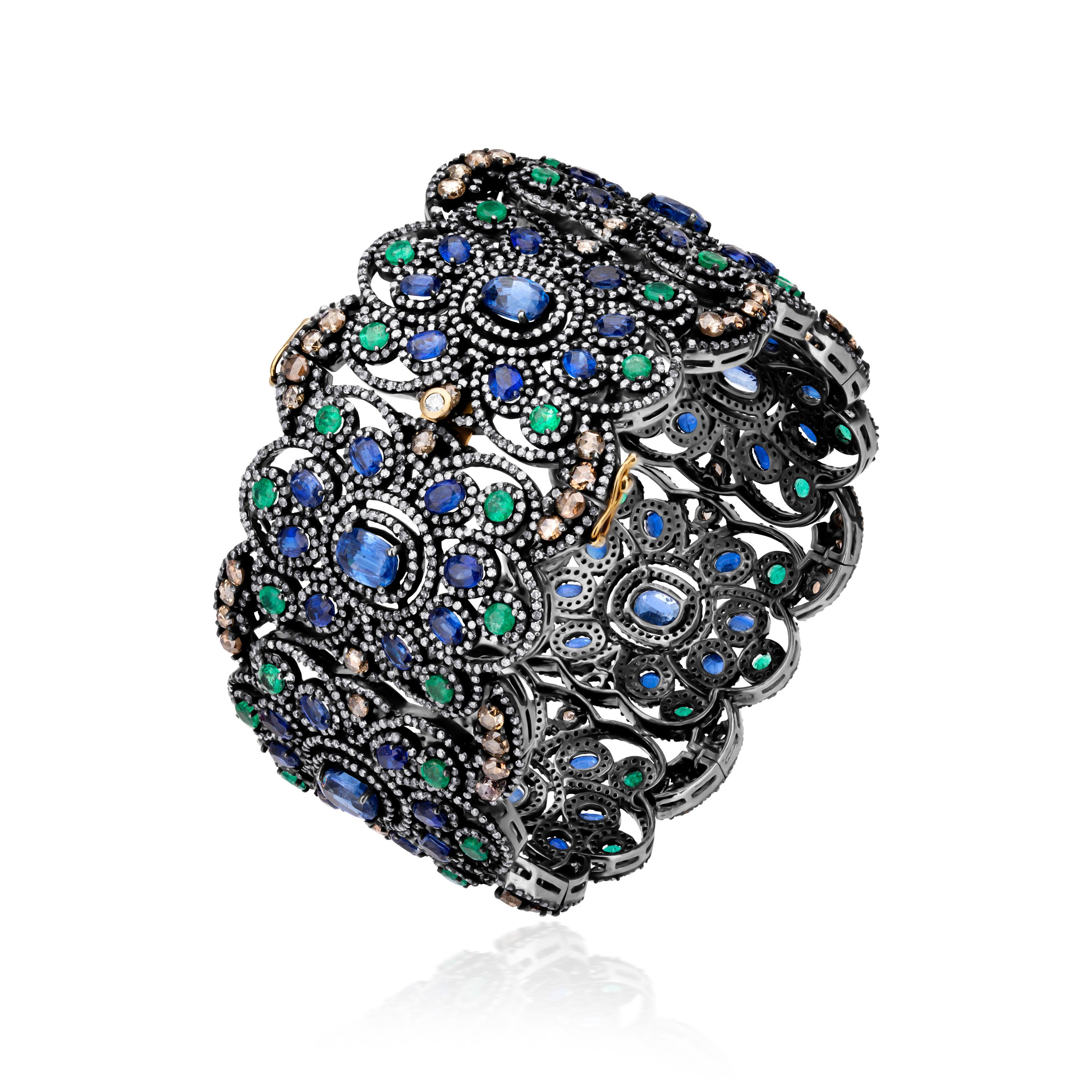 Motivos florales entrelazados se unen para formar esta majestuosa pulsera victoriana Nigaam. Cada motivo floral consta de una cianita azul ovalada en su centro. Cada cianita del centro está rodeada por 8 cianitas en forma circular. Las esmeraldas