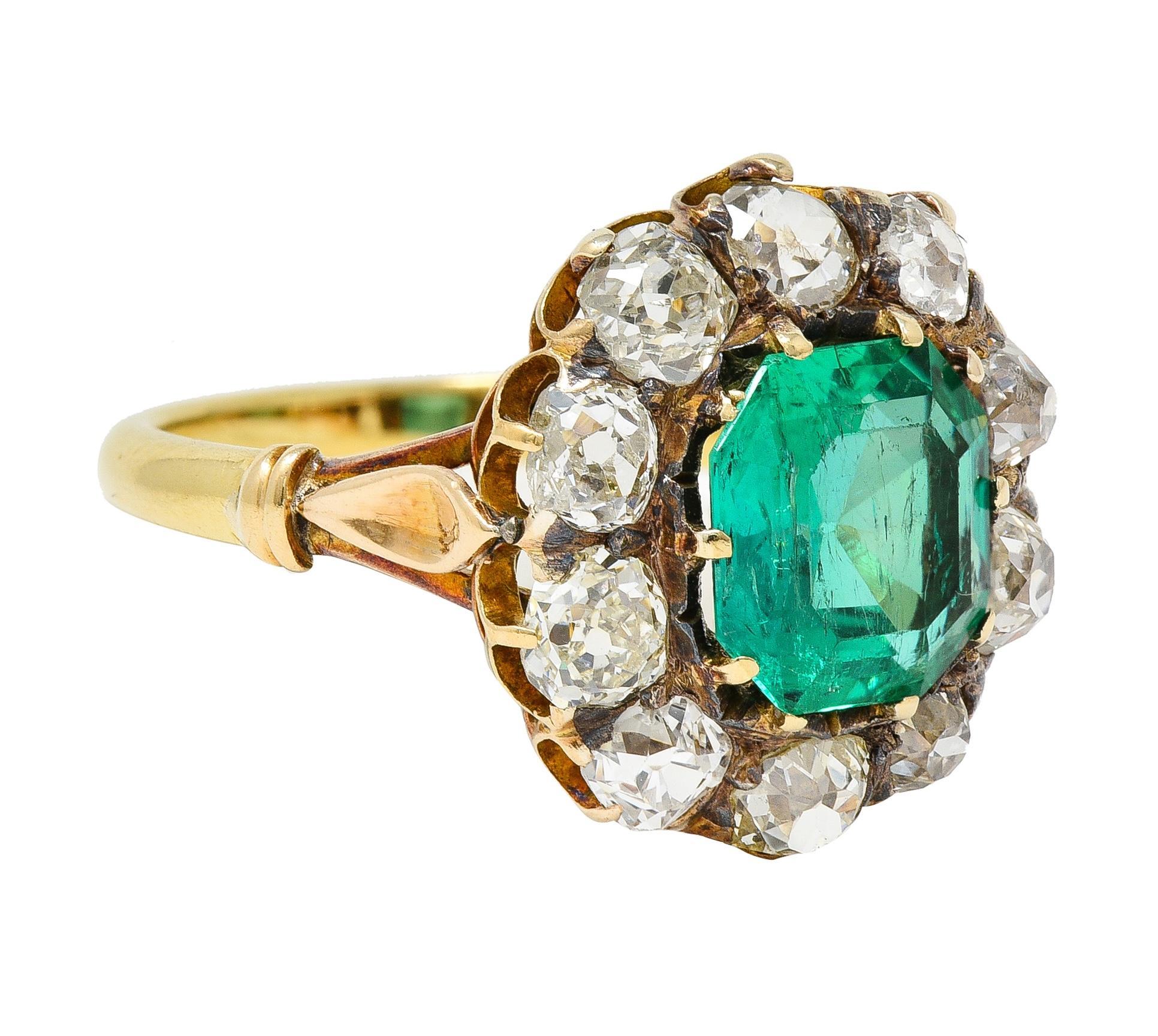 Centering an octagonal step-cut emerald weighing 2.04 carats - transparent medium green 
Natural Colombian in origin with minor traditional clarity enhancement(F2)
Prong set with a halo surround of old mine cut diamonds 
Weighing approximately 2.24