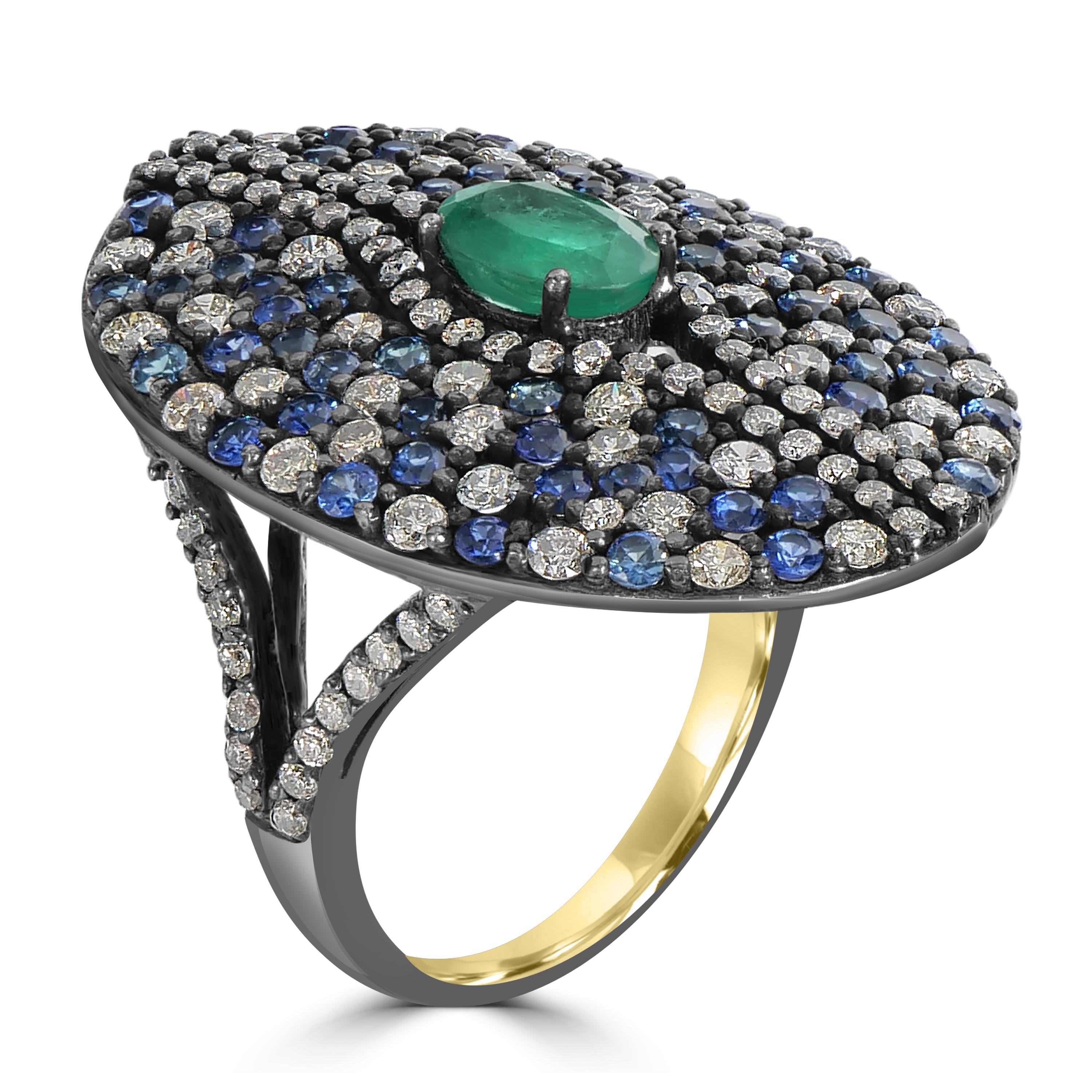 Step into the world of timeless elegance with the Victorian 4.3 Cttw. Emerald, Sapphire, and Diamond Split Shank Ring — a fusion of artistry and sophistication in 18k Gold and black rhodium silver. At its core, an oval emerald takes center stage, a