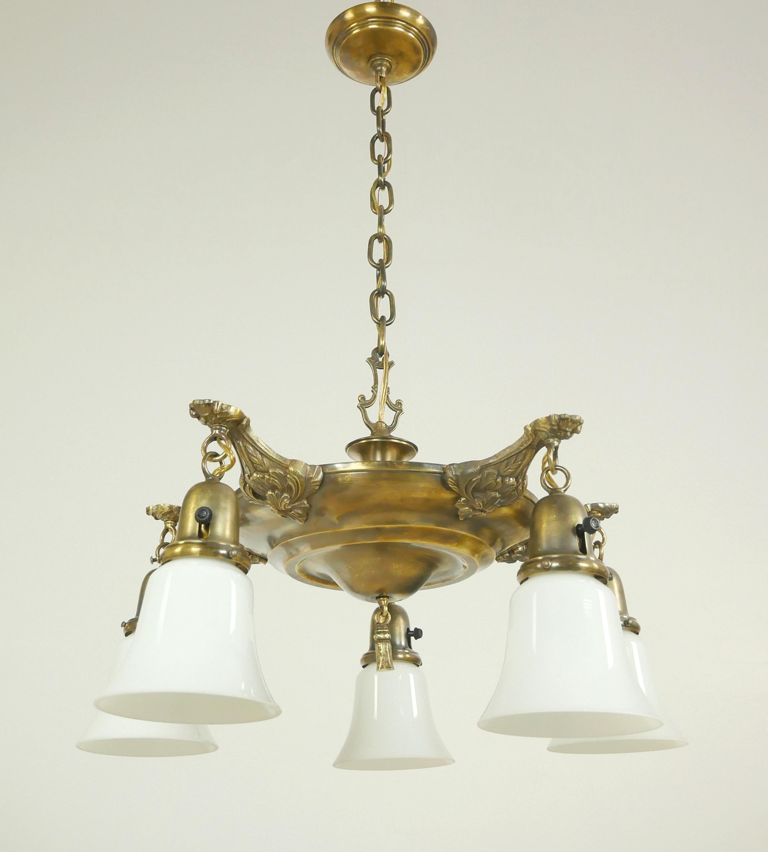 Victorian style pan pendant chandelier with five white shades, an antique brass ornate pan frame, and a newly made steel chain. This requires five standard medium base bulbs. Restored and ready to ship. Good condition with appropriate wear from age.