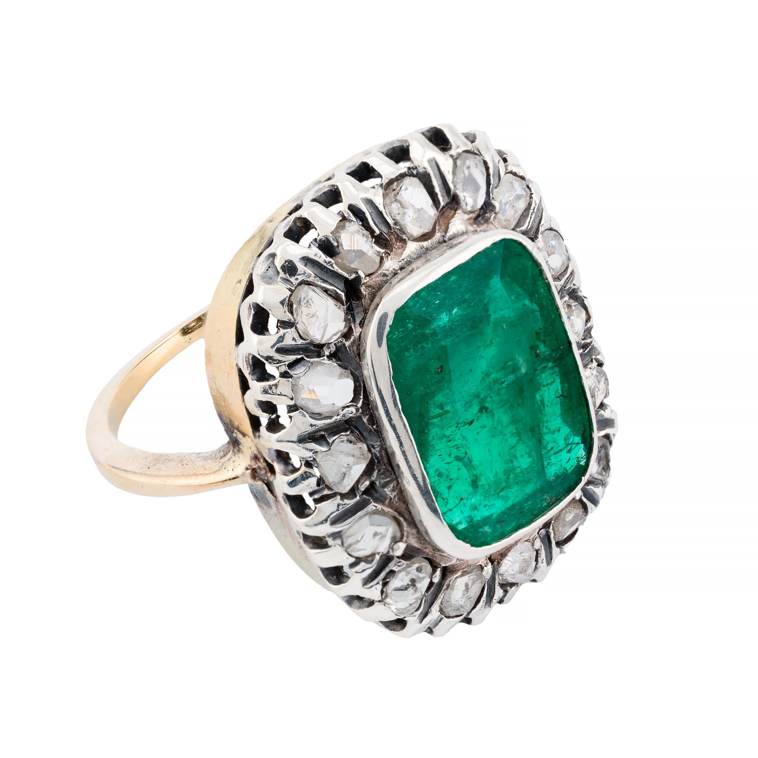 Aston Estate Jewelry Presents:

A striking statement ring featuring a 5.10 carat antique cushion cut emerald, radiating a rich green hue. The centerpiece is elegantly surrounded by rose cut diamonds, totaling 0.90 carats. The diamonds exhibit a