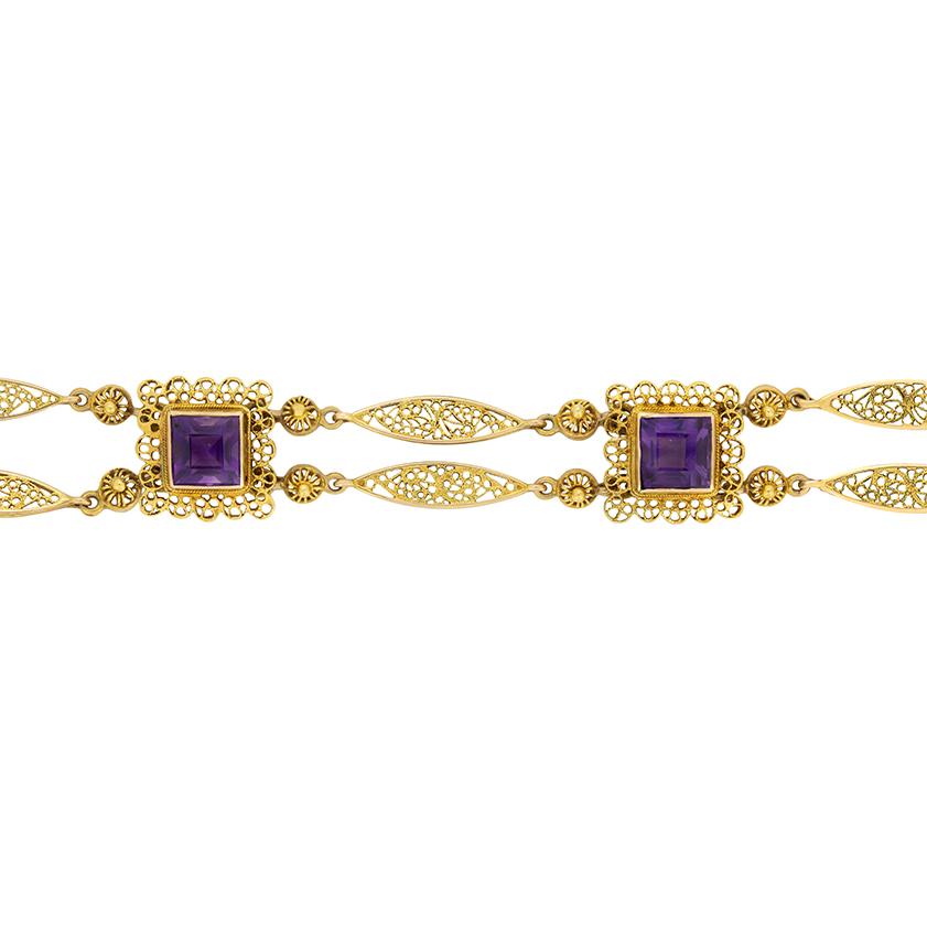 Questo affascinante bracciale risalente al 1880 è incastonato con cinque ametiste taglio Carrs. Tutte e cinque le gemme sono incastonate in oro giallo 18ct con un motivo intricato realizzato a mano. Sono tutti collegati tra loro da due catene d'oro